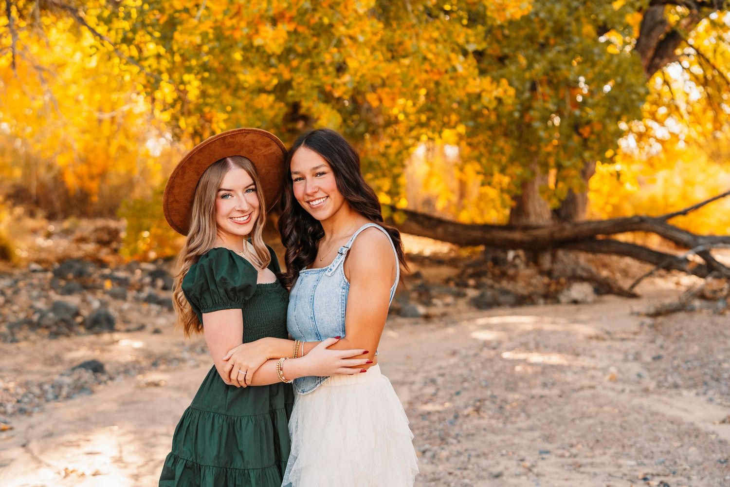 Friends share candid moments during sunset with golden trees in background.