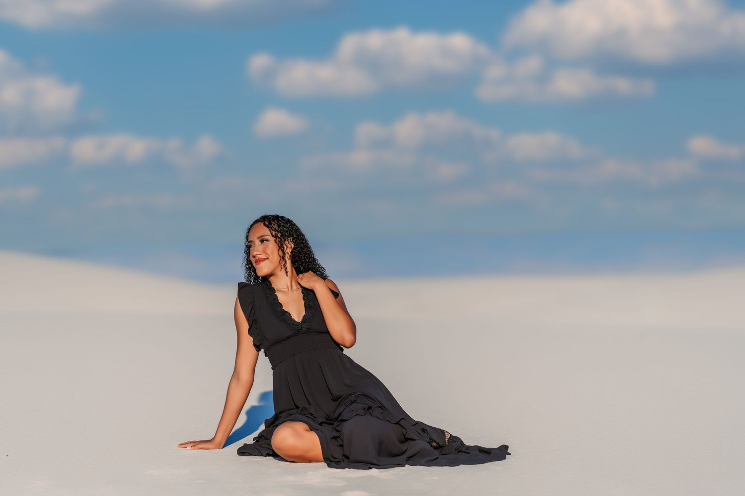 Artistic portrait session against blue sky and clouds with dramatic poses.