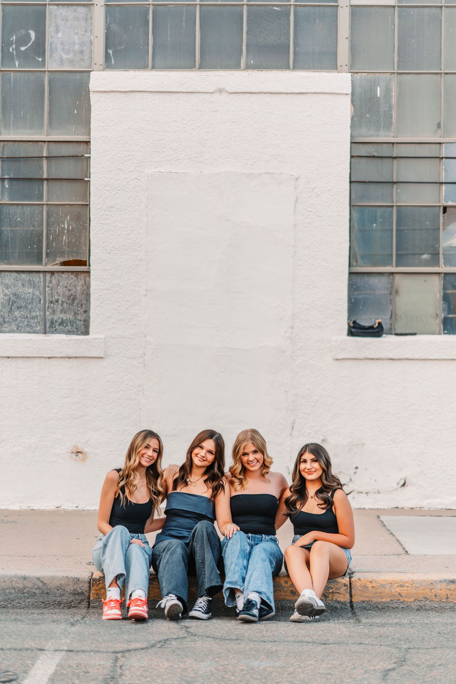 Group sitting casually against a wall wearing jeans and sneakers in a candid urban photo shoot.varsity jacket
cheer uniform
soccer ball