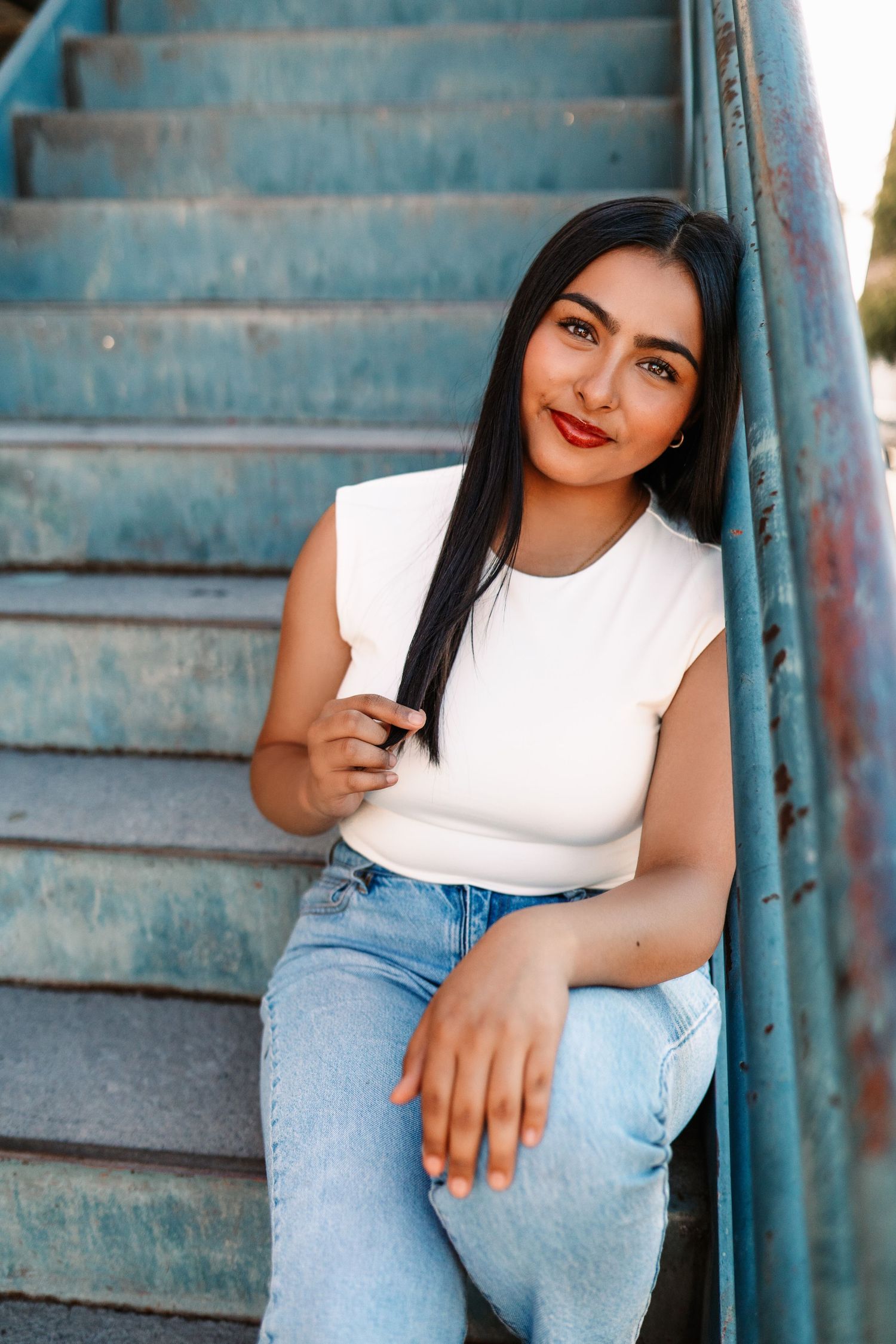 Casual fashion portraits on blue concrete steps featuring white top and light denim jeans.