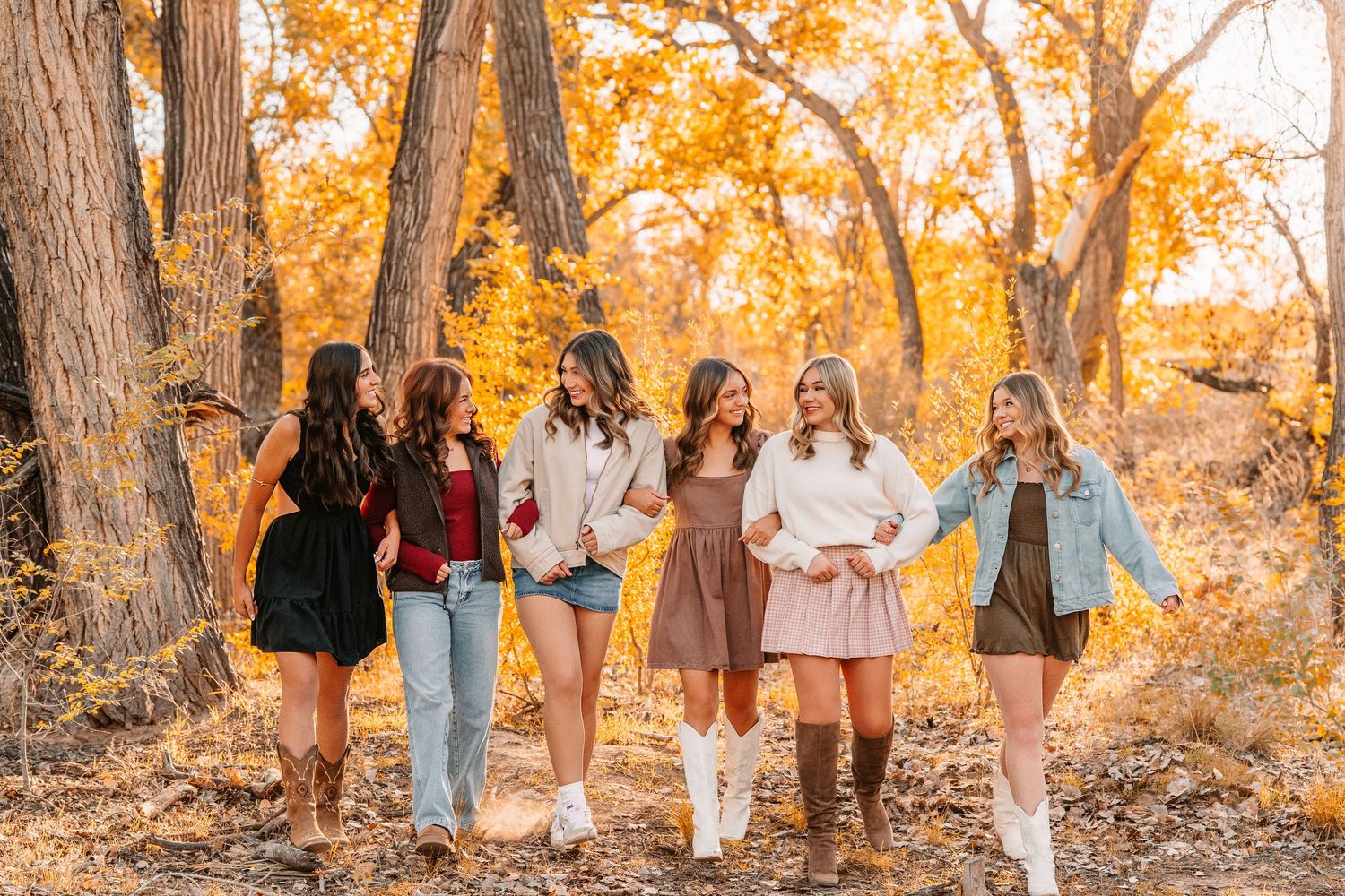 Group photo session in an autumn setting with golden leaves and tall trees.