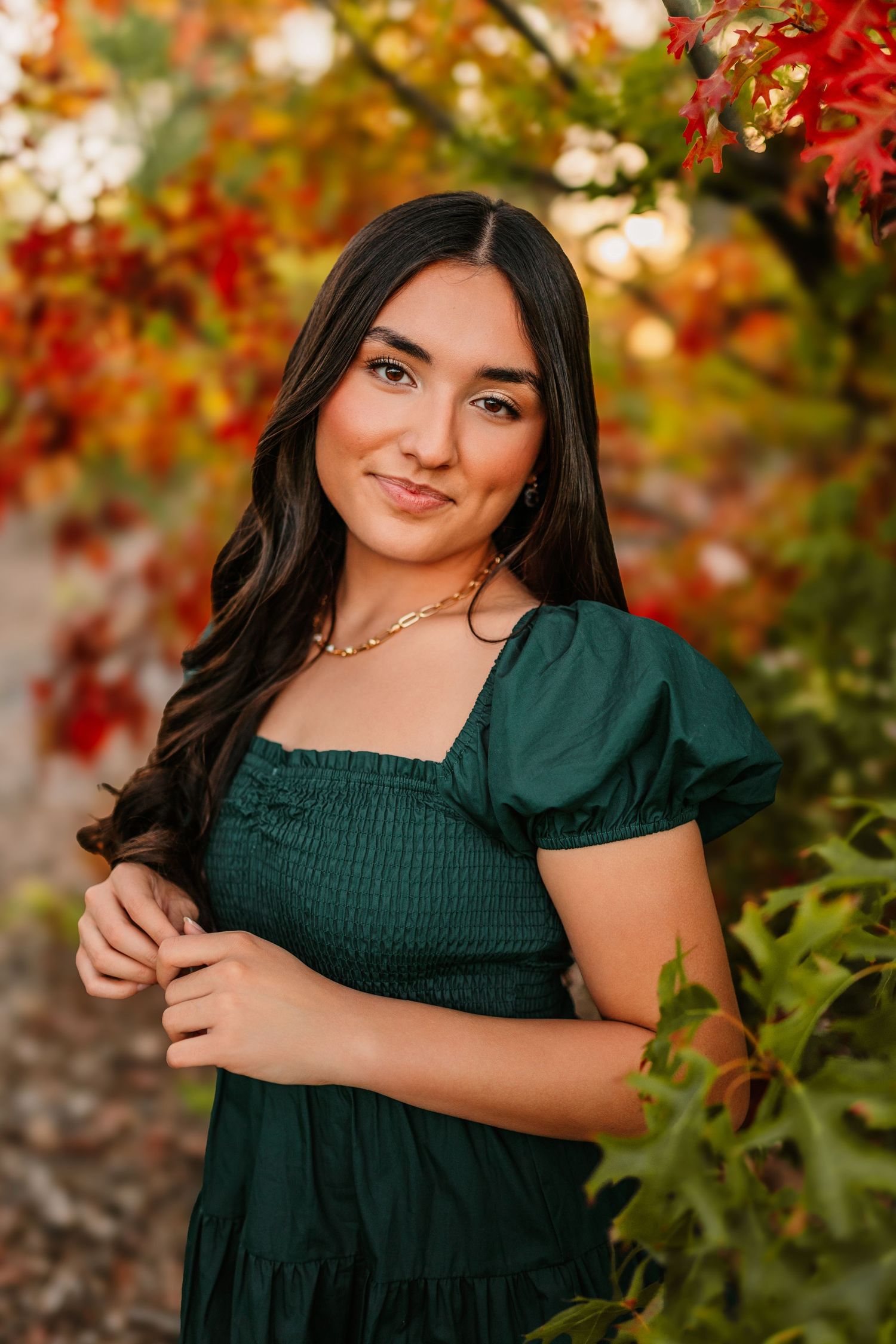 A dark green smocked dress photographed against autumn foliage.