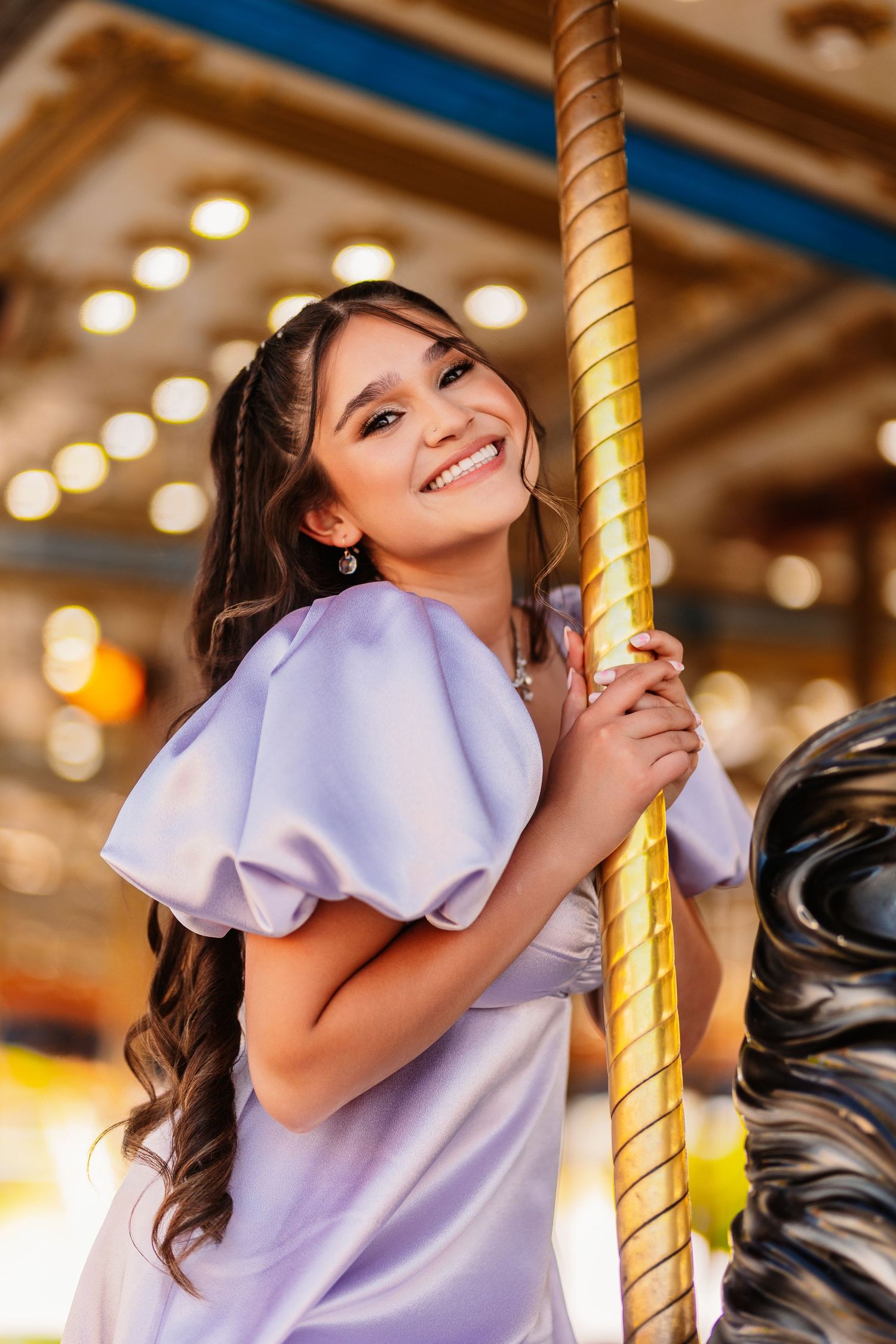A lavender ruffle sleeve top photographed on a carousel with warm lighting.