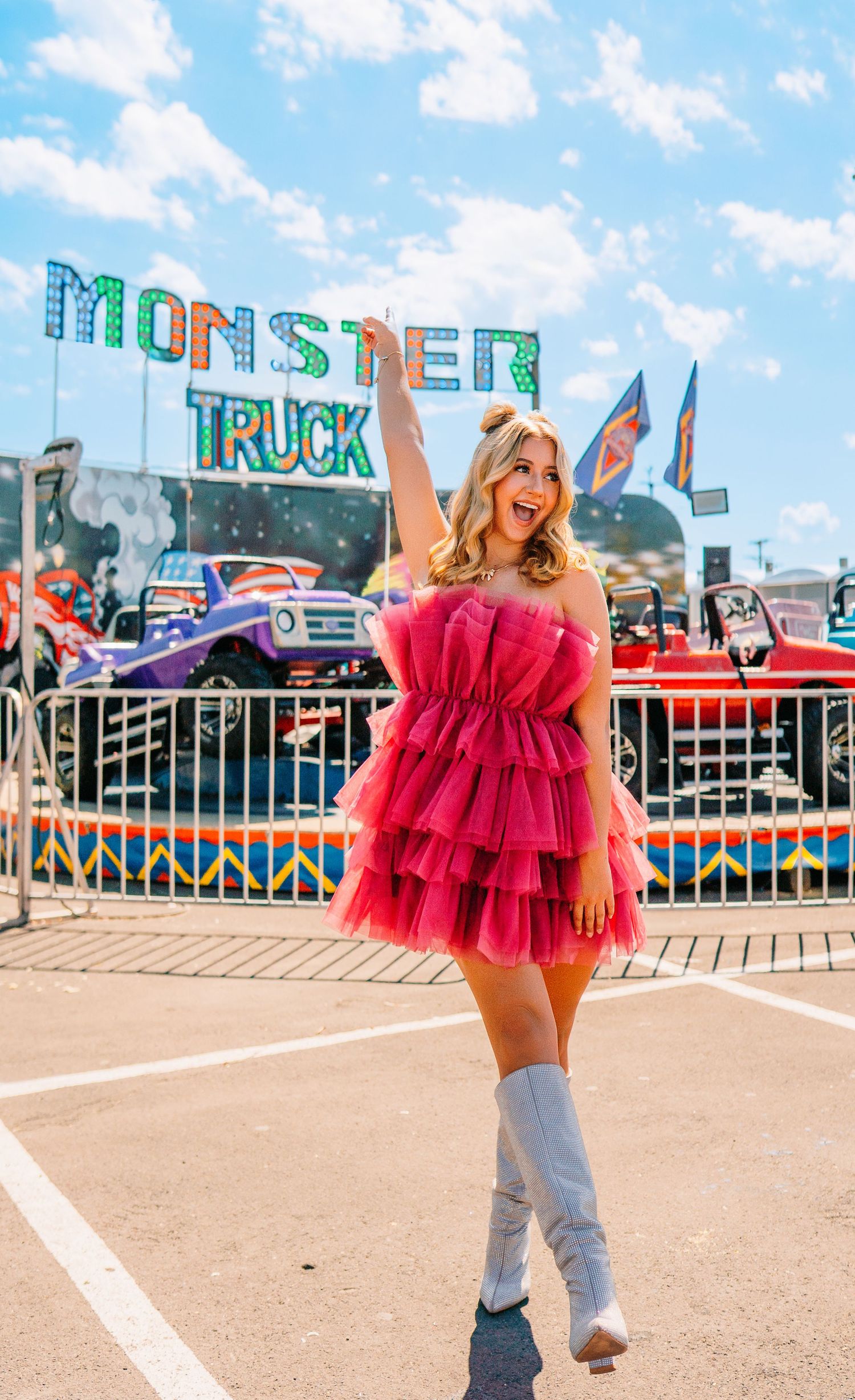 A vibrant carnival scene with monster truck signage and a pink tulle dress.