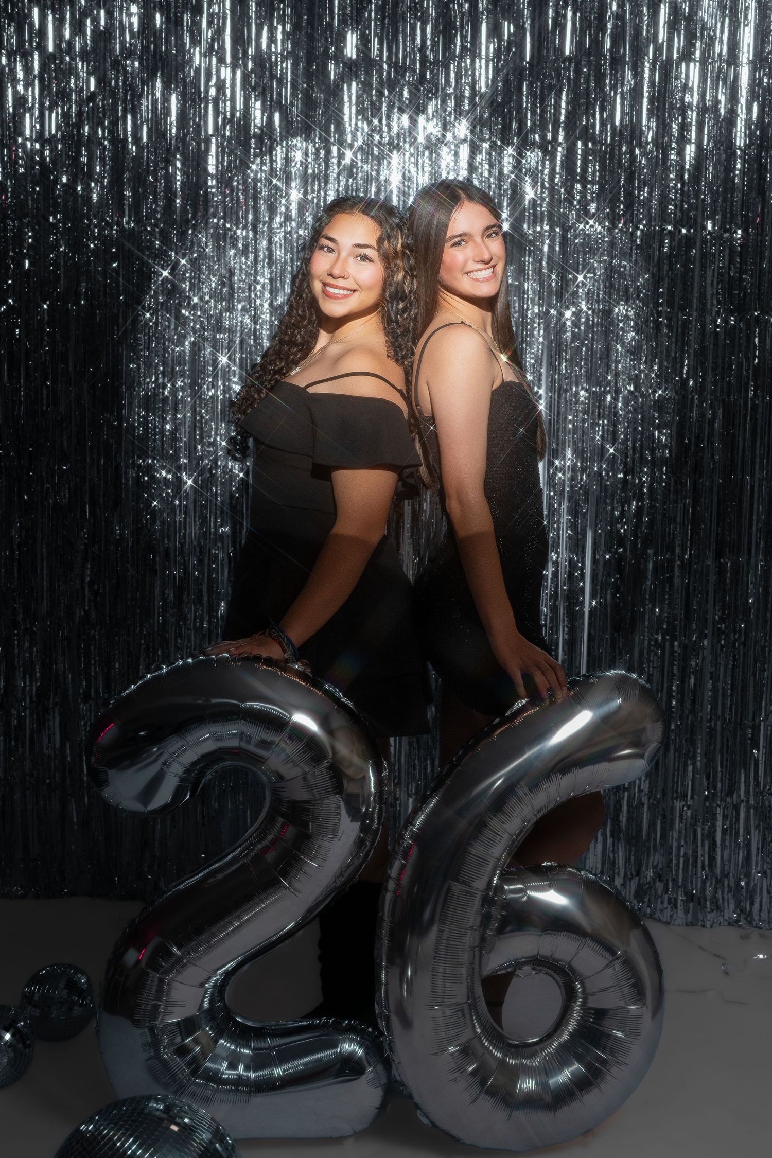 Two friends pose together with large black number balloons against a silver tinsel backdrop.senior session
Albuquerque senior photographer
