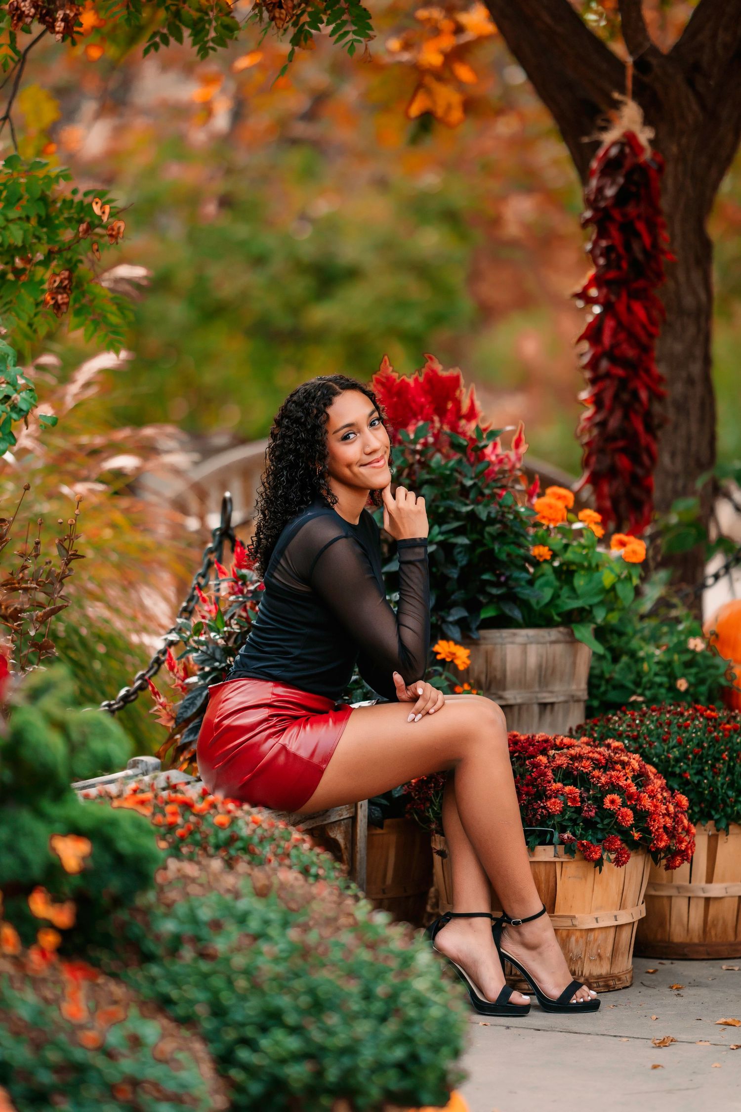 Autumn garden photoshoot with red skirt among fall flowers and foliage.
