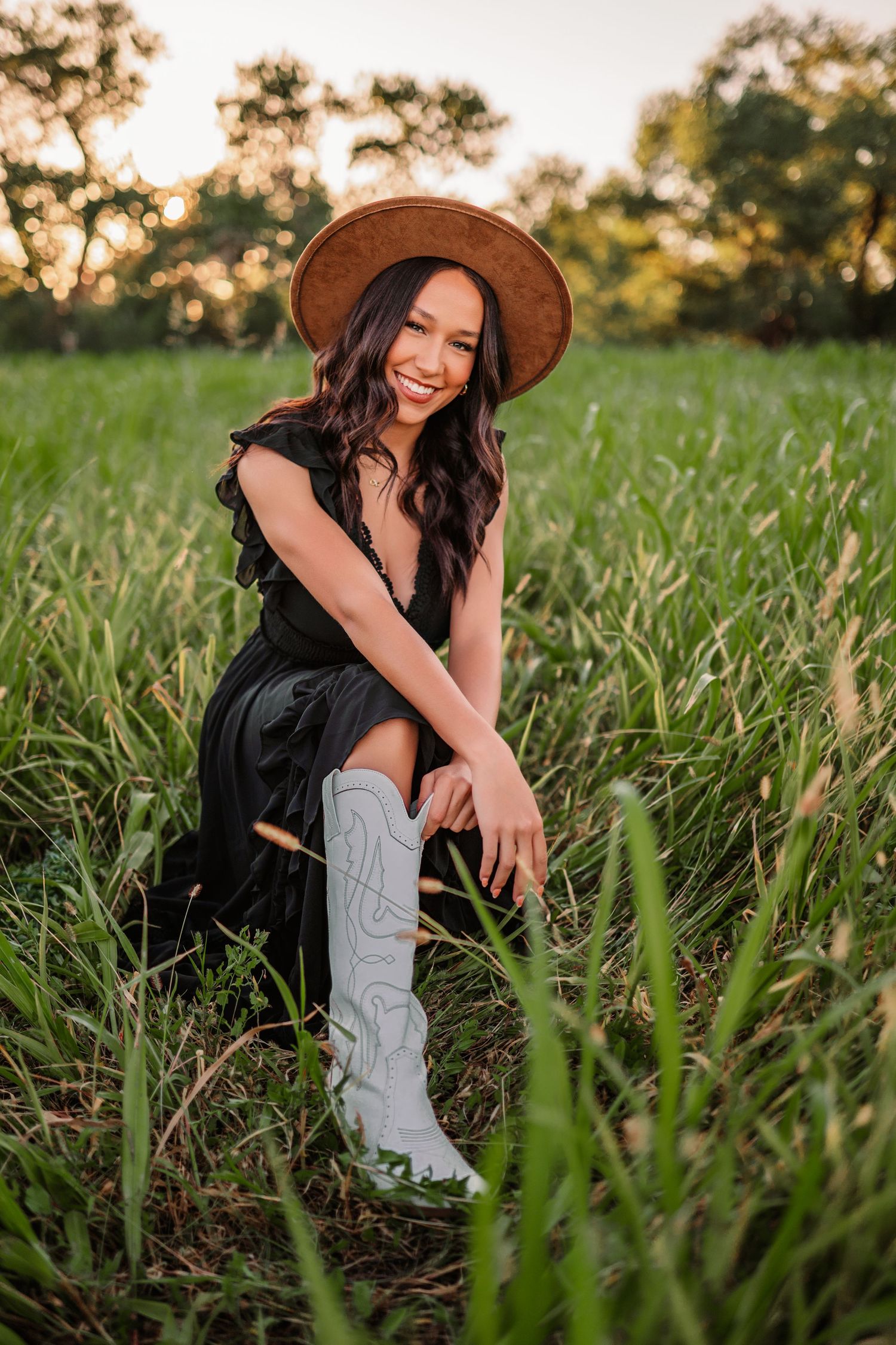 Rustic outdoor portrait session in tall grass featuring western boots and a brown hat.portraits, images, session, photo shoot
