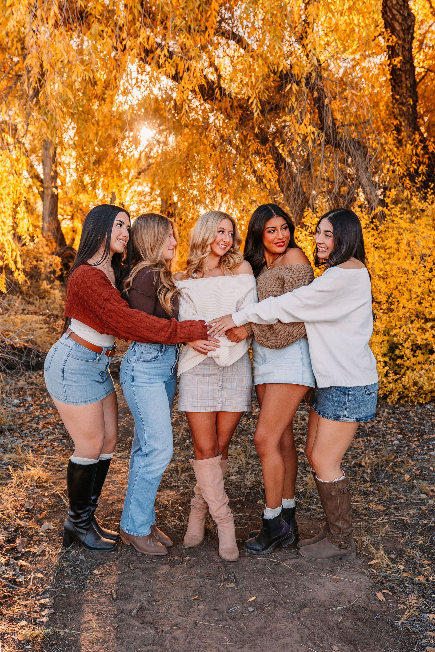 Group photo showing boots and casual outfits against autumn foliage background.