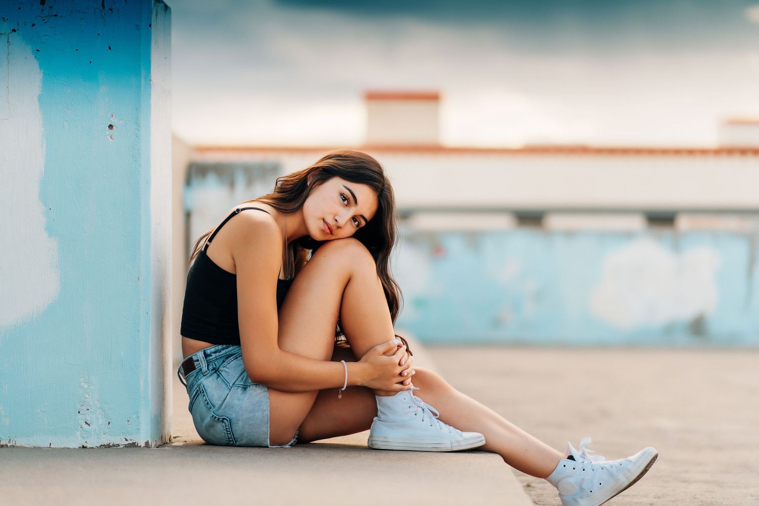 Modern urban photoshoot with blue wall backdrop and casual poses.
