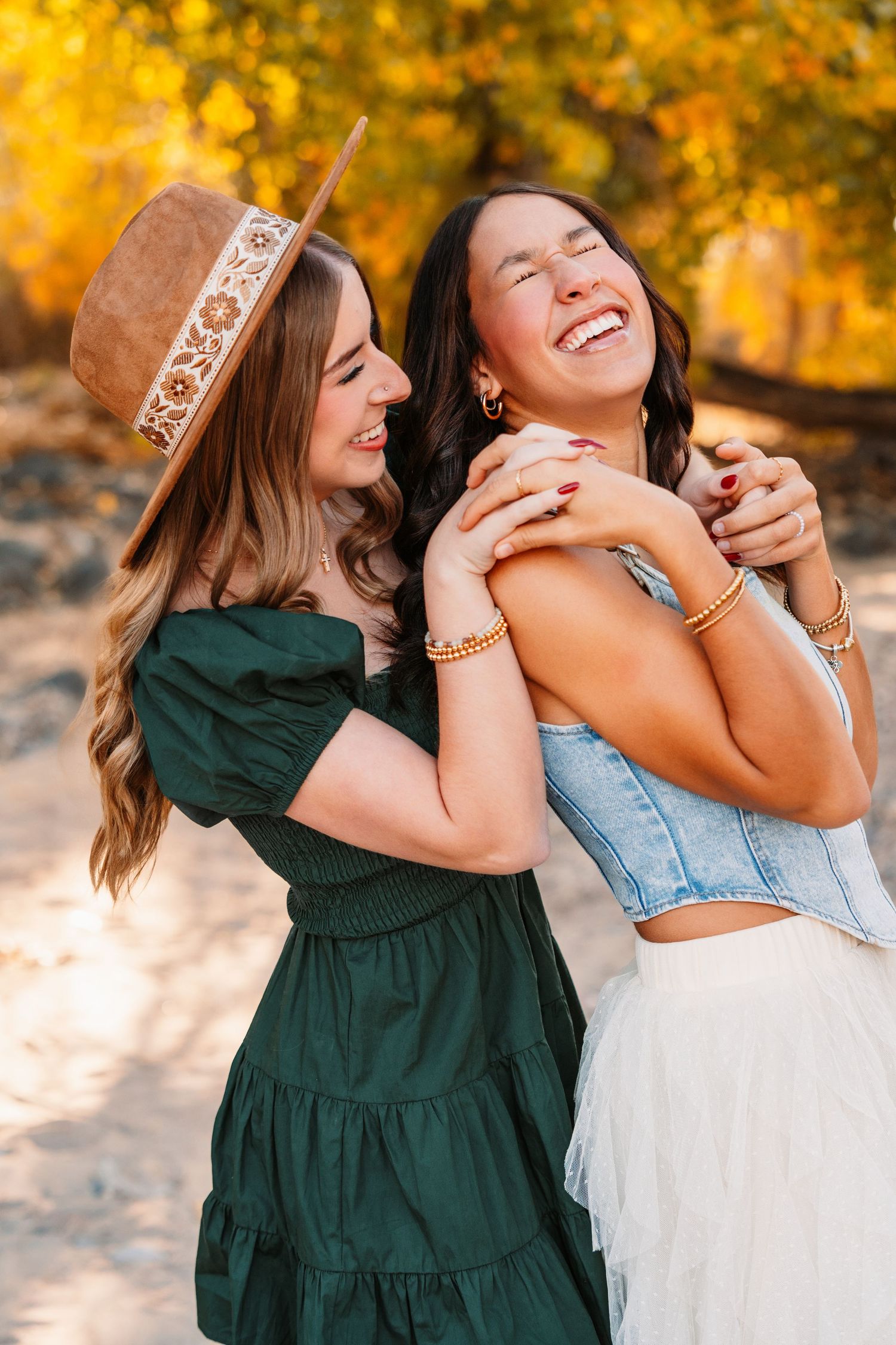 Two friends share joyful laughter against autumn foliage background.