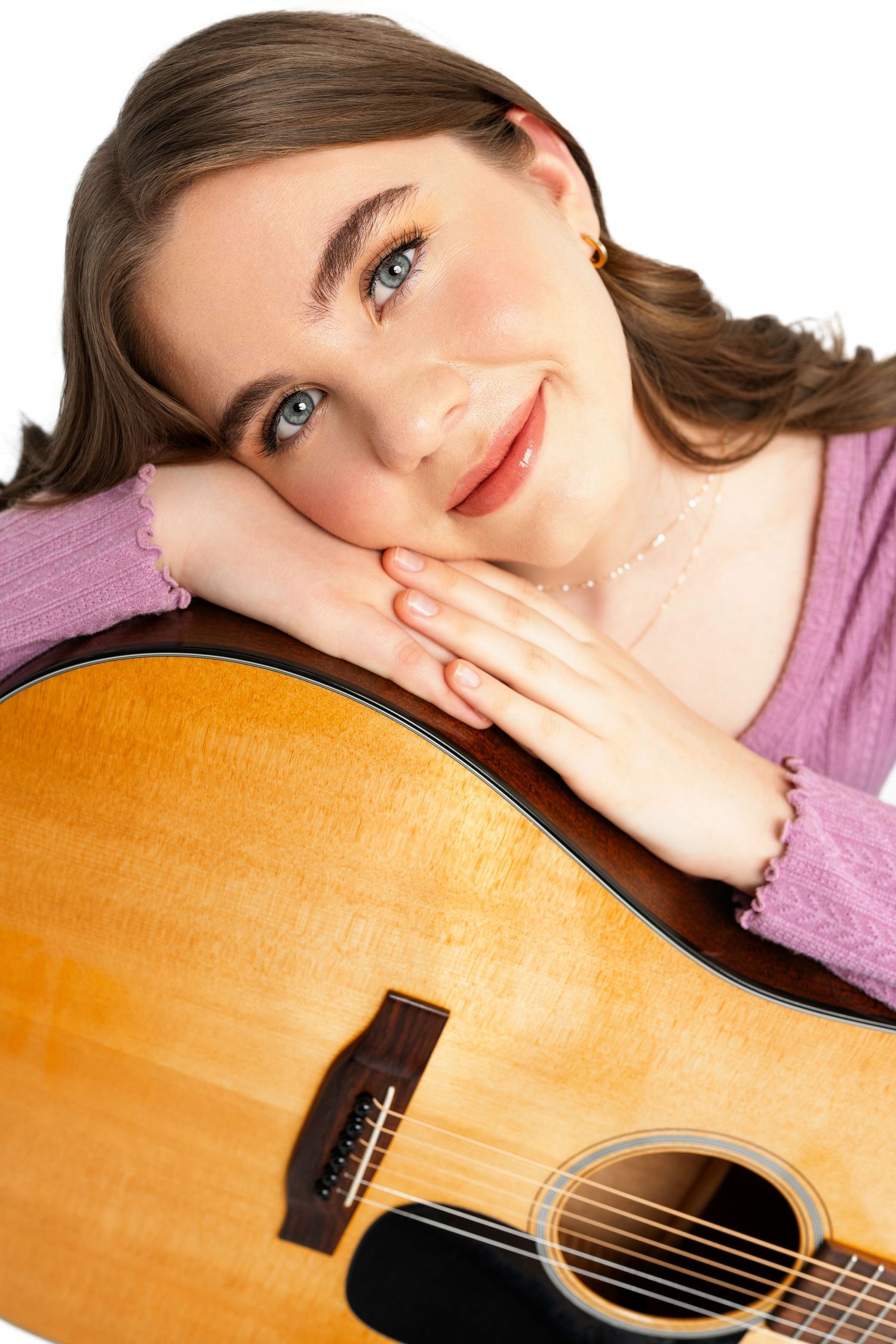 Close-up shots showing someone posing with an acoustic guitar against a simple background.