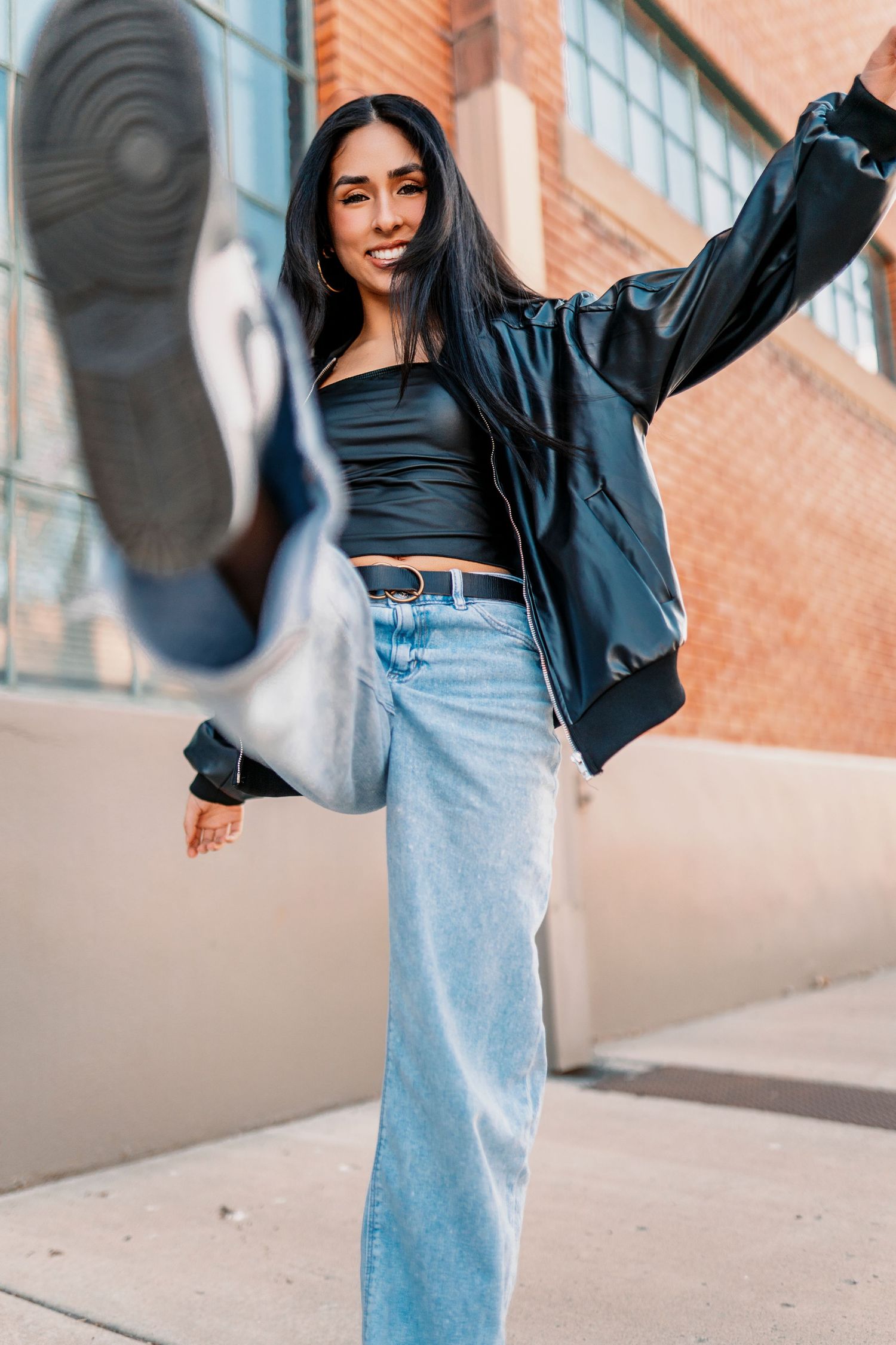 Urban fashion series with denim and leather jacket against brick wall.