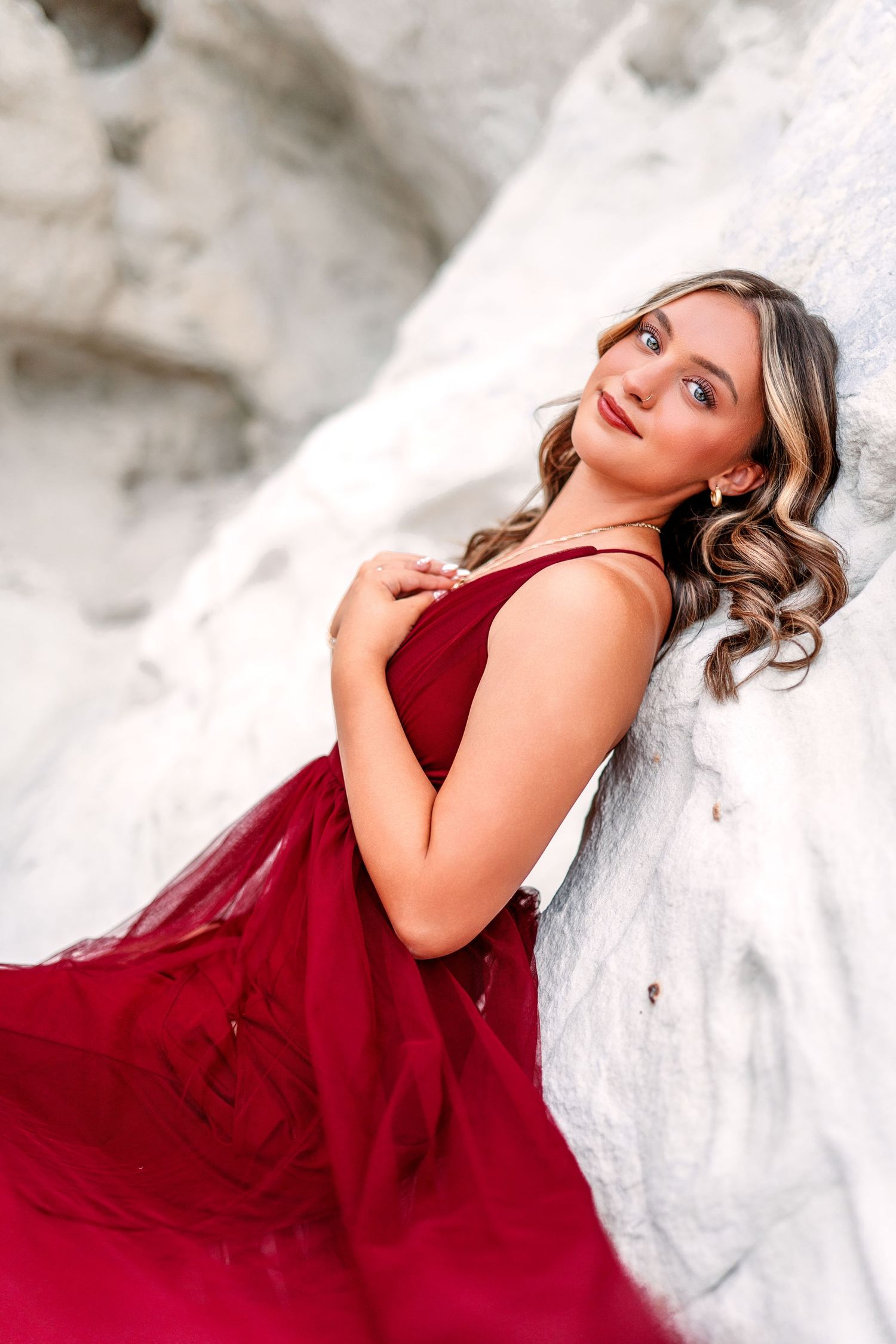 Portrait of woman in flowing red gown against white rock formation.