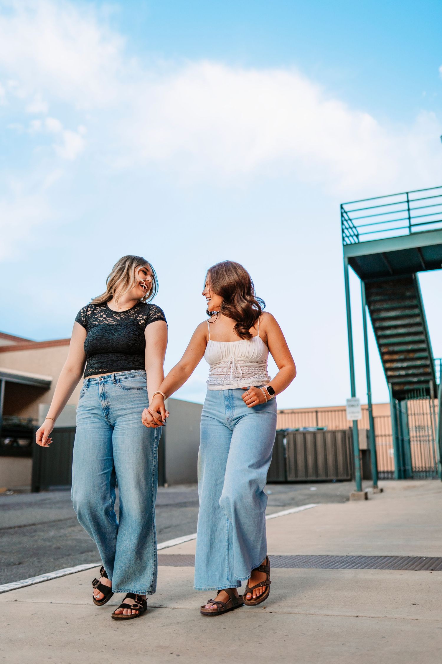 Walking feet photo of friends in jeans and sandals on urban concrete.