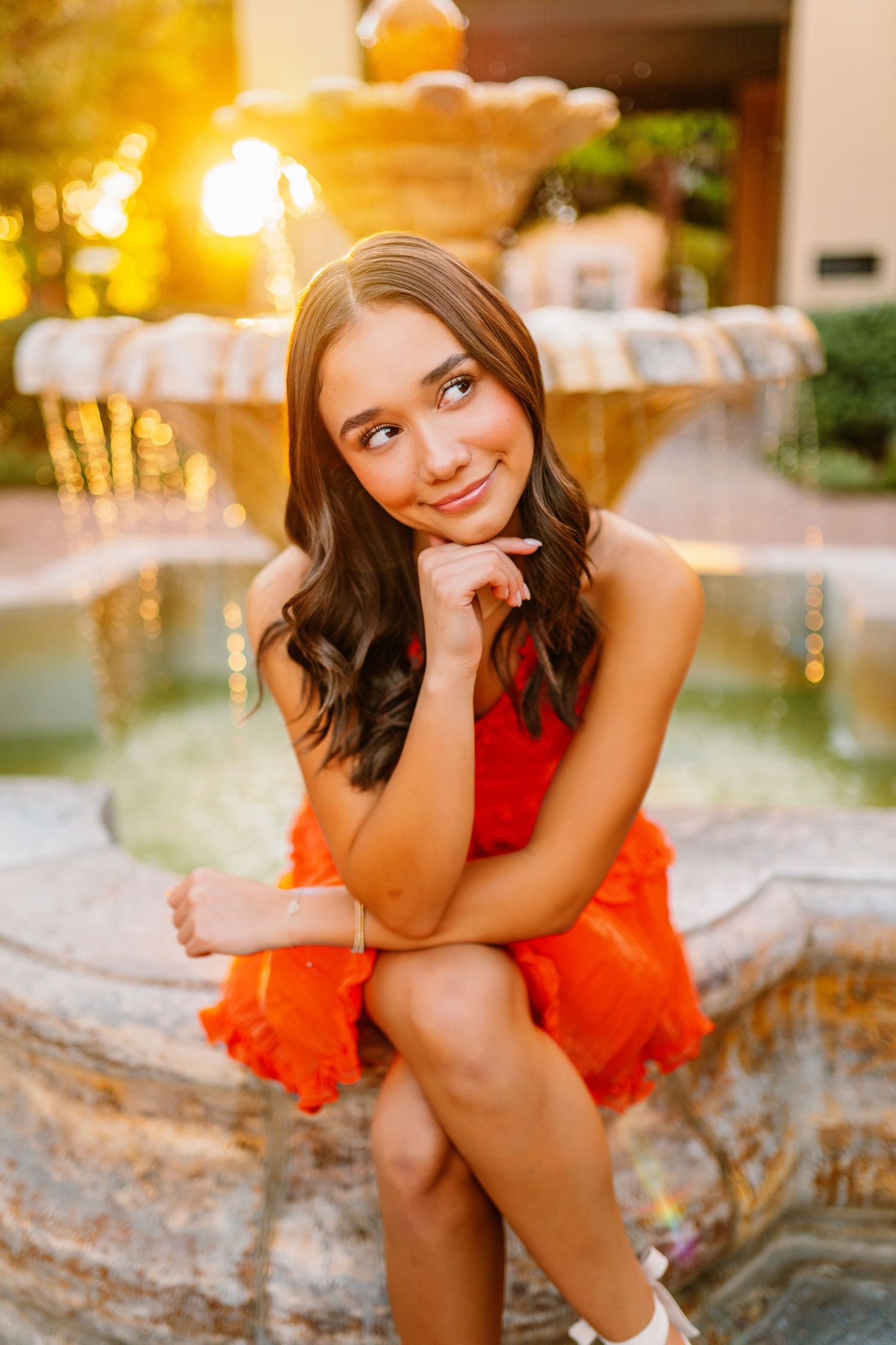 Portrait series by a fountain wearing vibrant orange dress during golden hour.