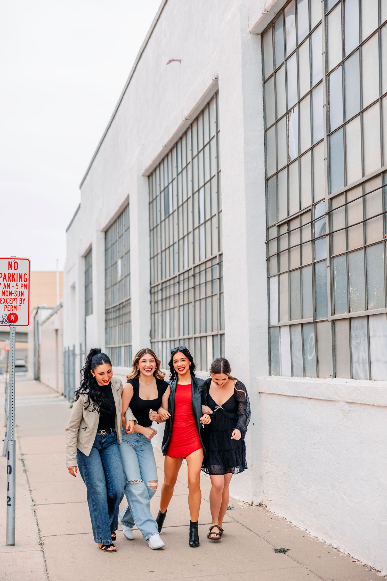 Group walking together along white industrial building with large windows.