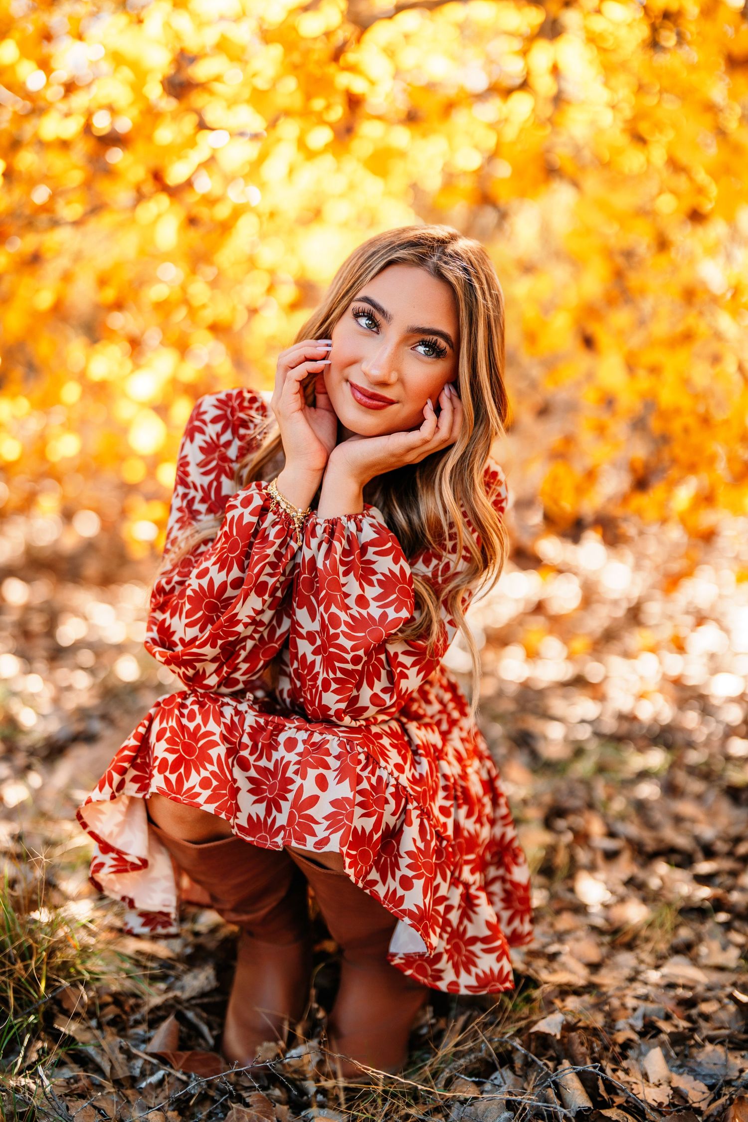 Fall fashion portraits in red floral dress against vibrant orange autumn foliage.