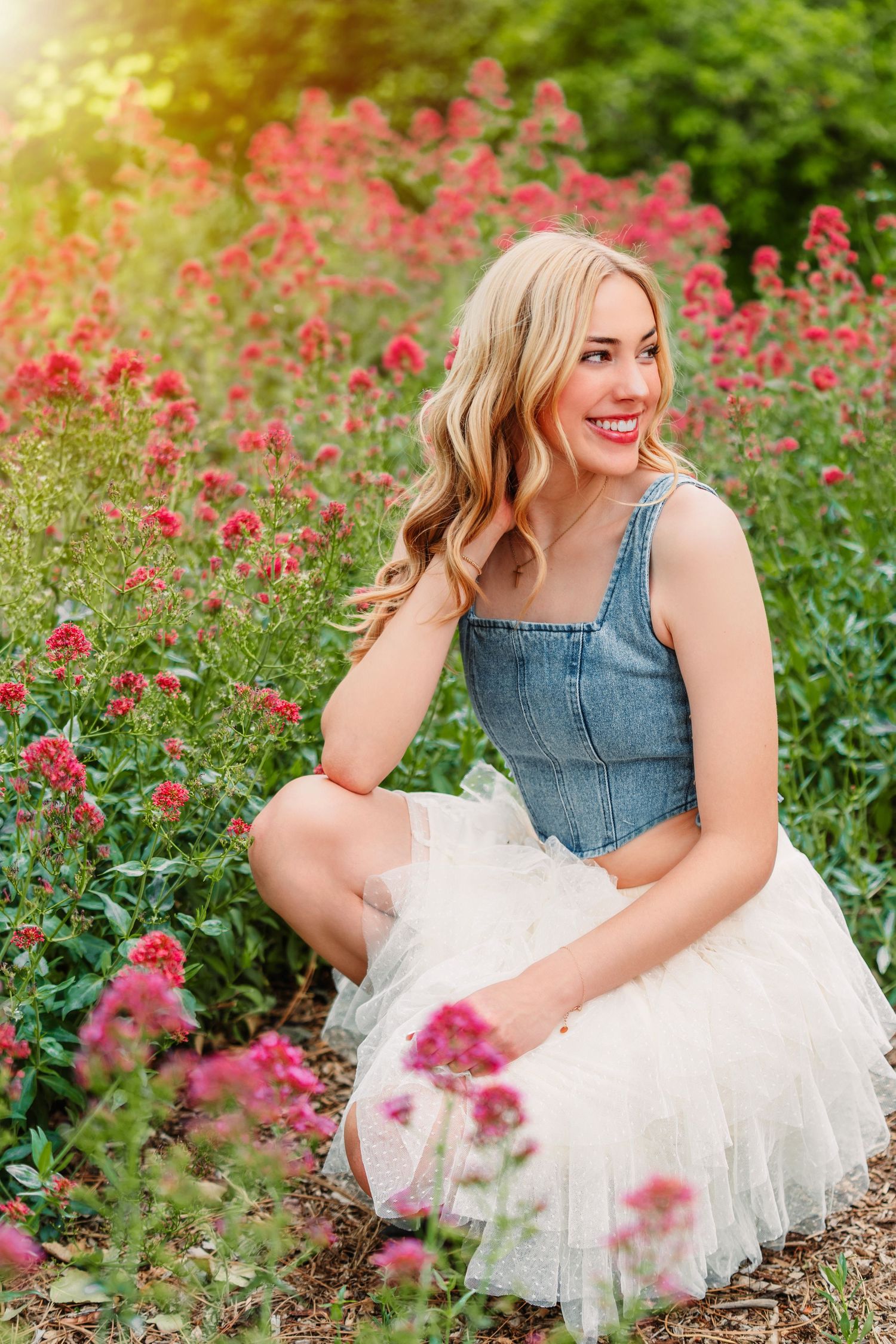A dreamy portrait session in a garden with vibrant pink flowers and a denim and tulle dress combination.