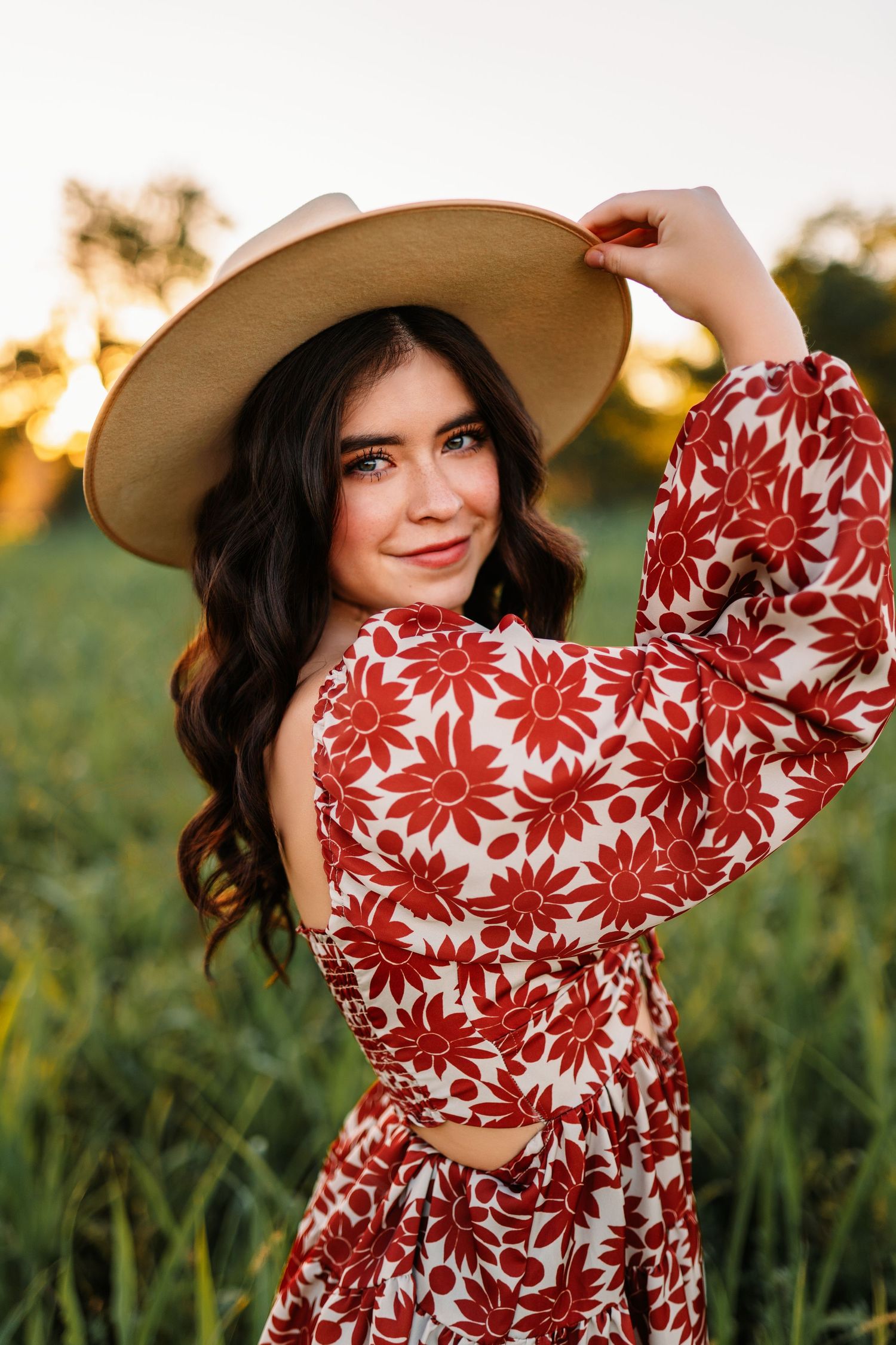 A floral red and white dress with puff sleeves photographed in a golden field at sunset.