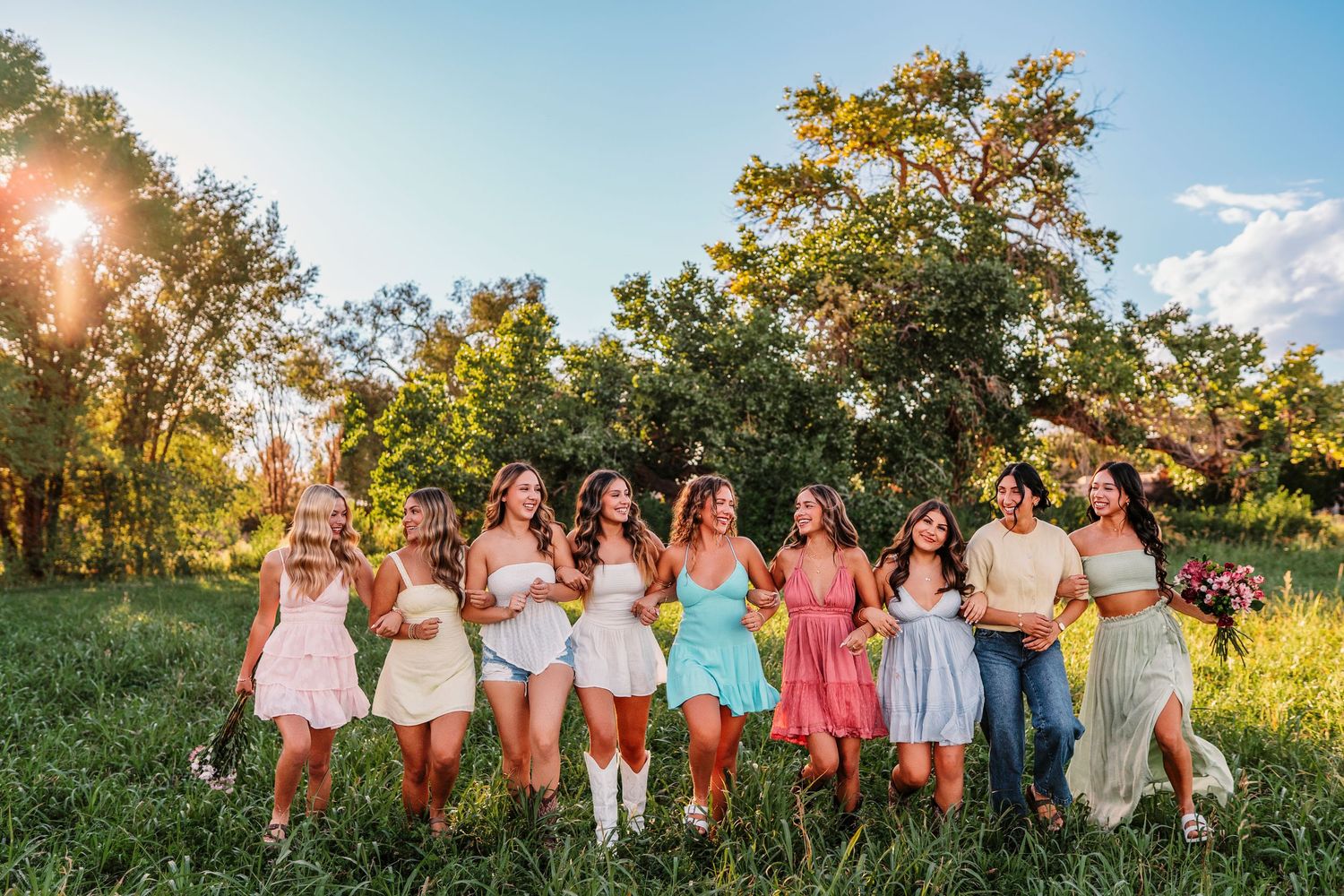 Group photo of people in coordinated pink and white outfits posing in a sunny field.
