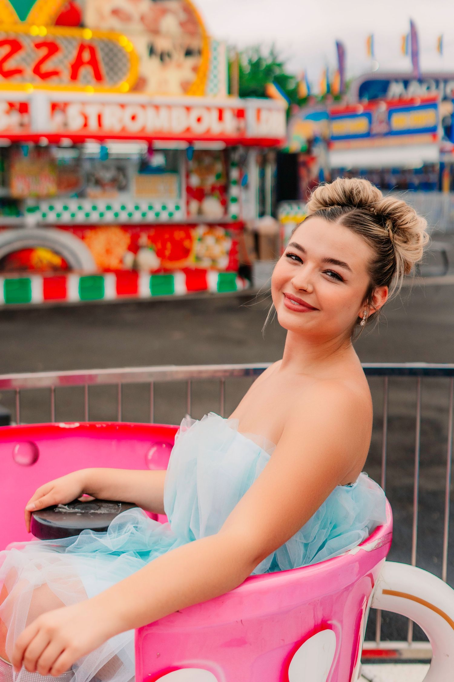 Playful carnival-themed portrait session featuring pastel blue dress at an amusement park.