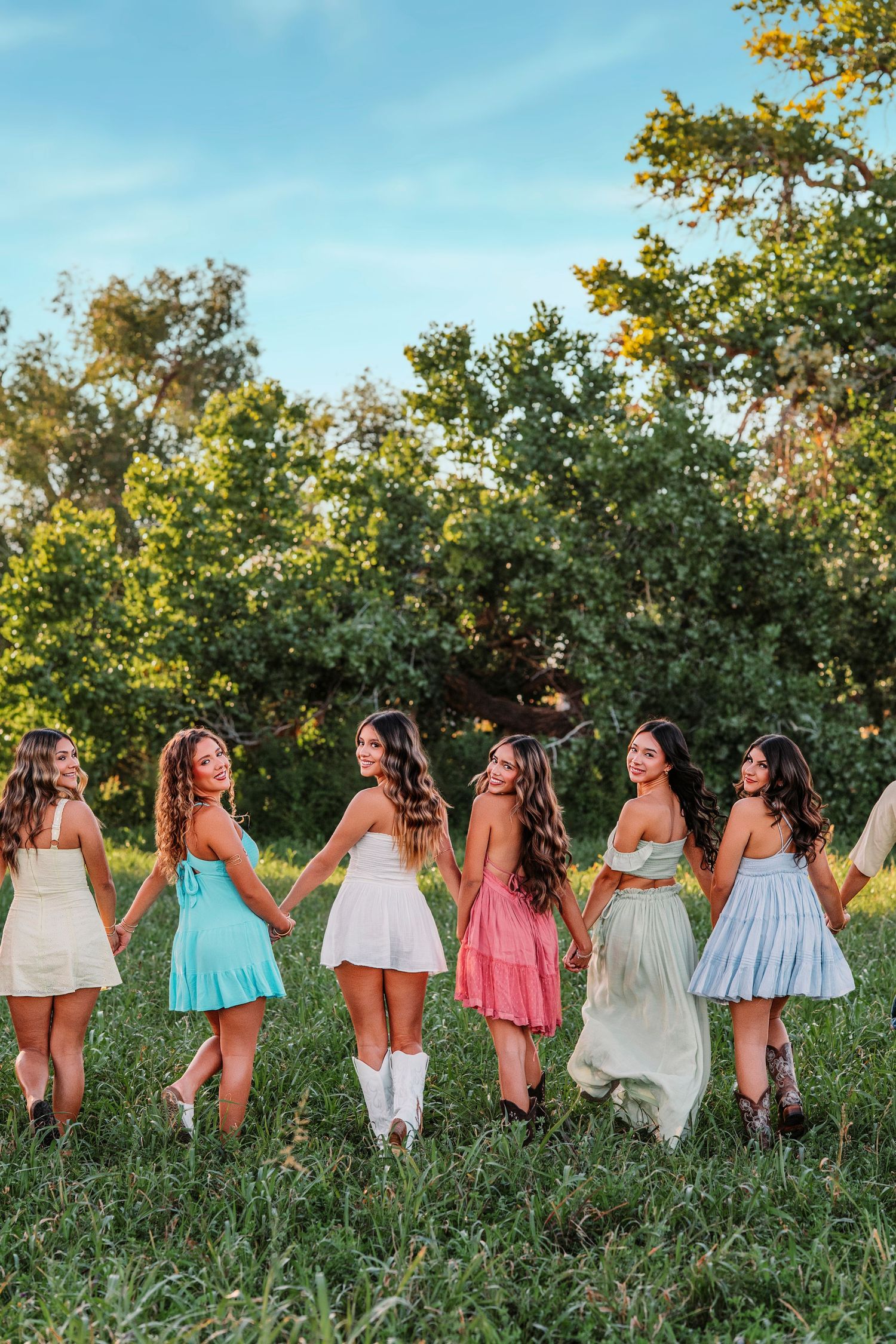Line of people in colorful summer dresses pose holding hands in a grassy field. senior session
Albuquerque senior photographer