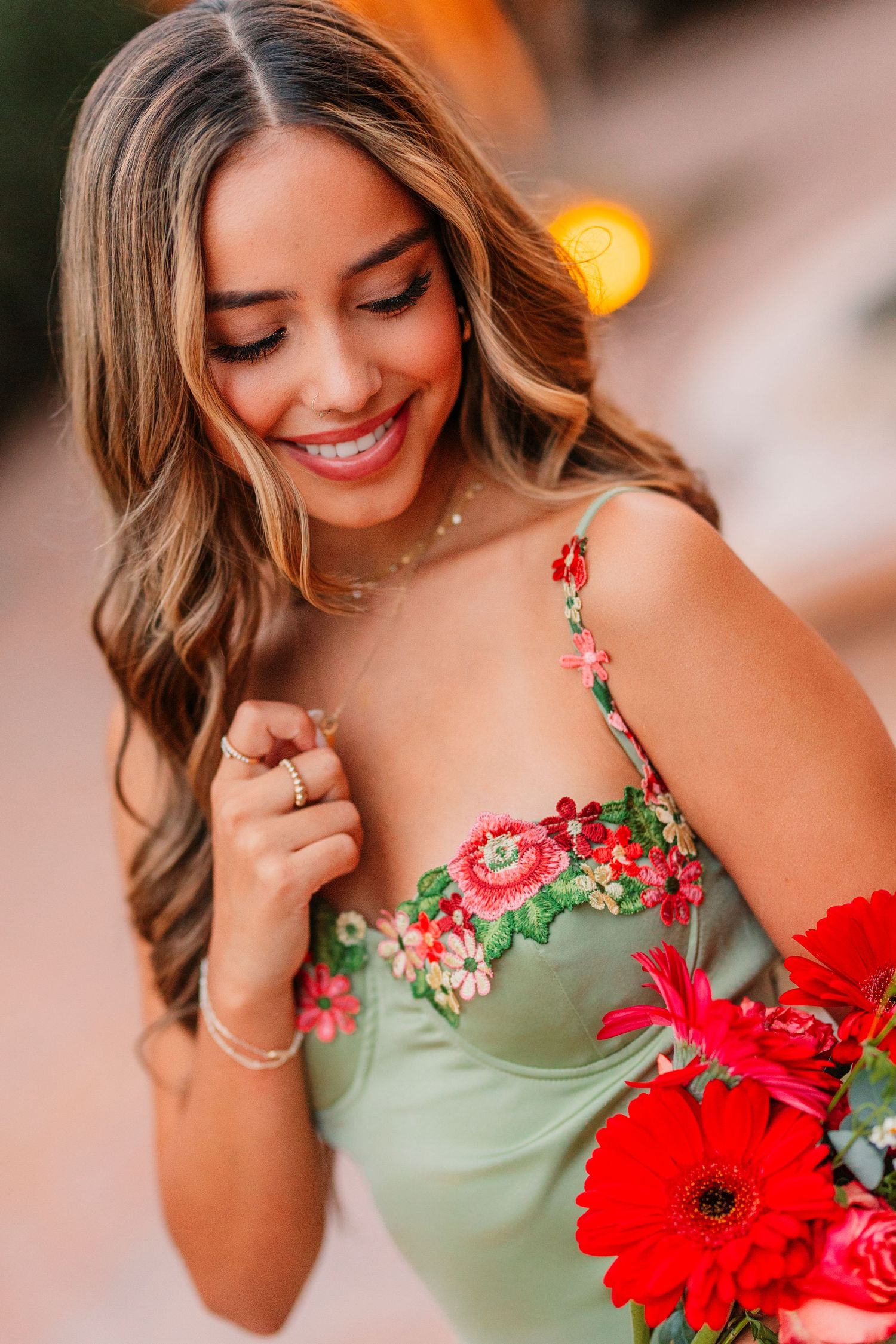 Close-up portrait with mint green floral dress and red gerbera daisy in warm lighting.