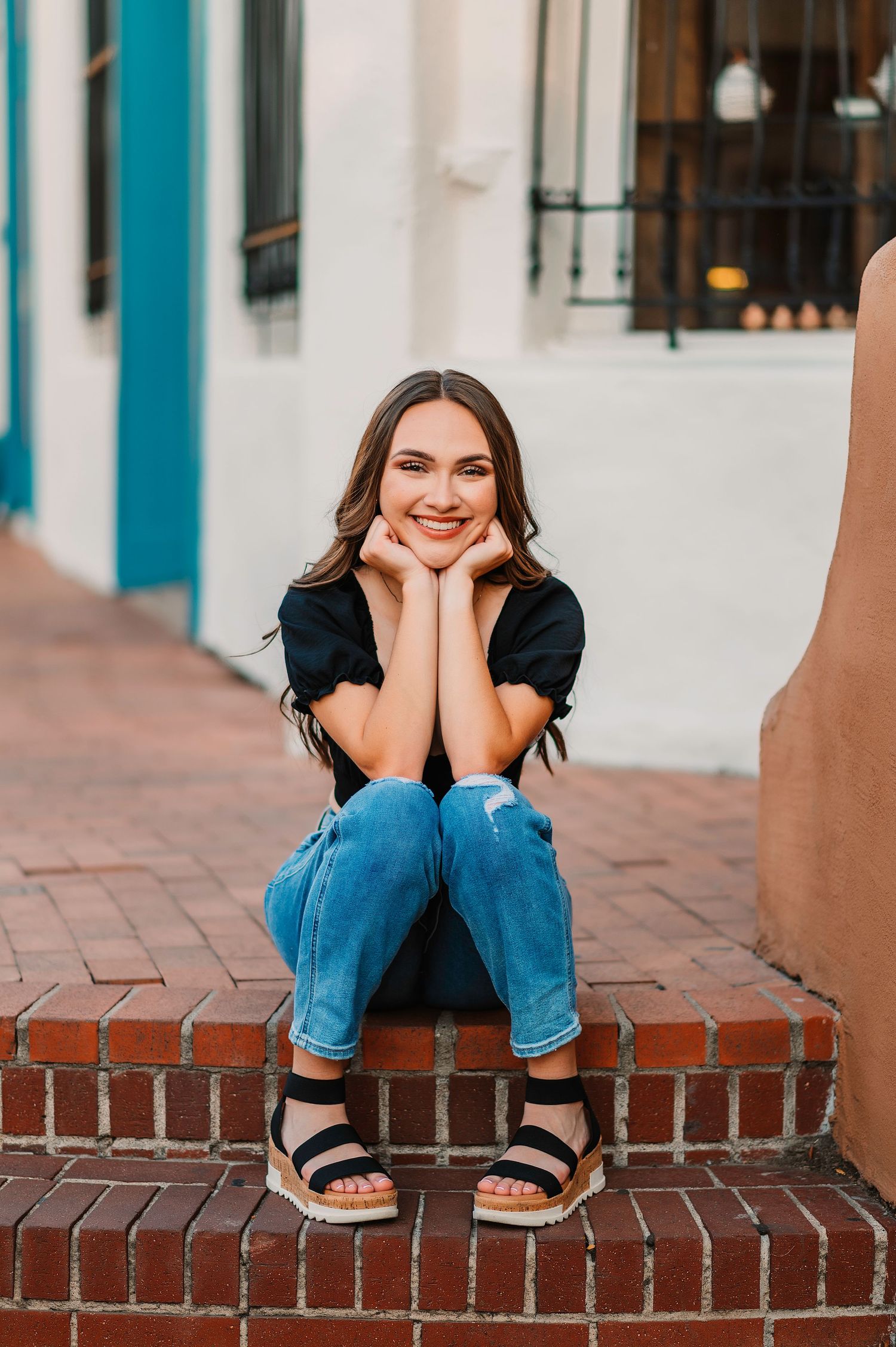 Relaxed poses on brick steps with turquoise trim building backdrop.