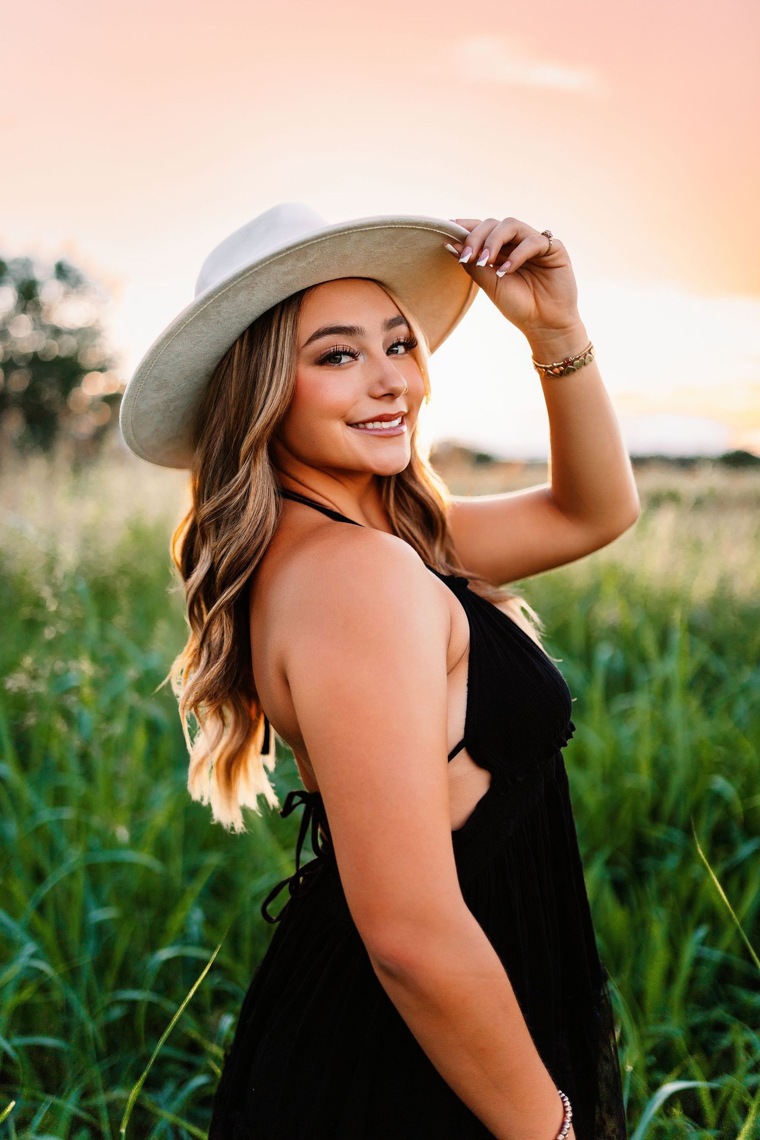 Portrait series in a cornfield at sunset wearing a black dress and cowboy hat.