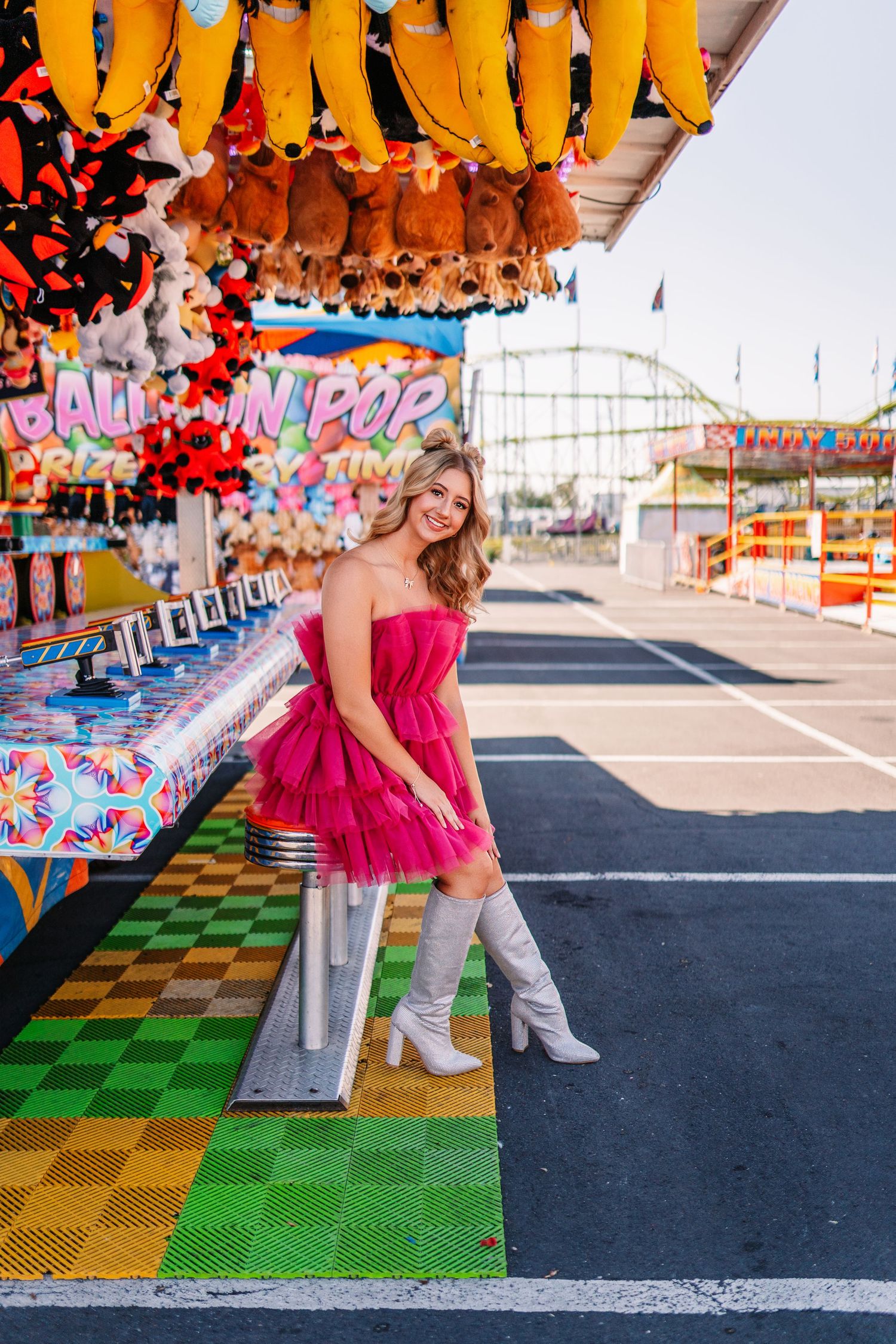 Pink ruffled dress stands out against carnival games with checkerboard flooring.