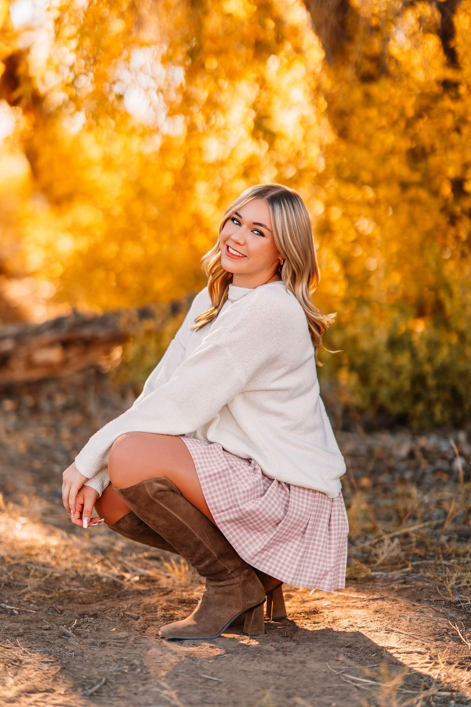 Autumn portraits in cream sweater and plaid skirt with golden sunset lighting.