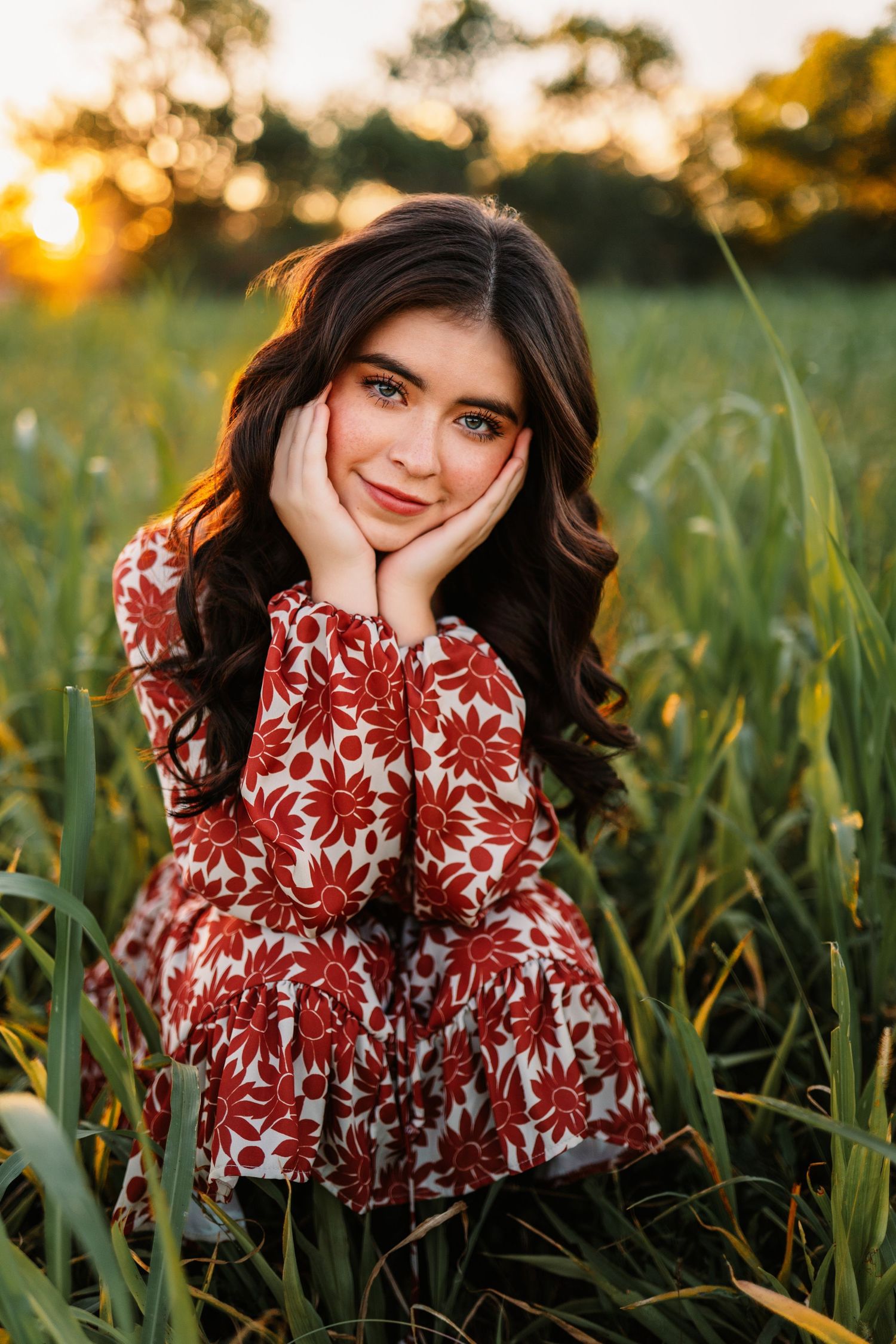 A red floral dress photographed in a grassy field during golden hour.