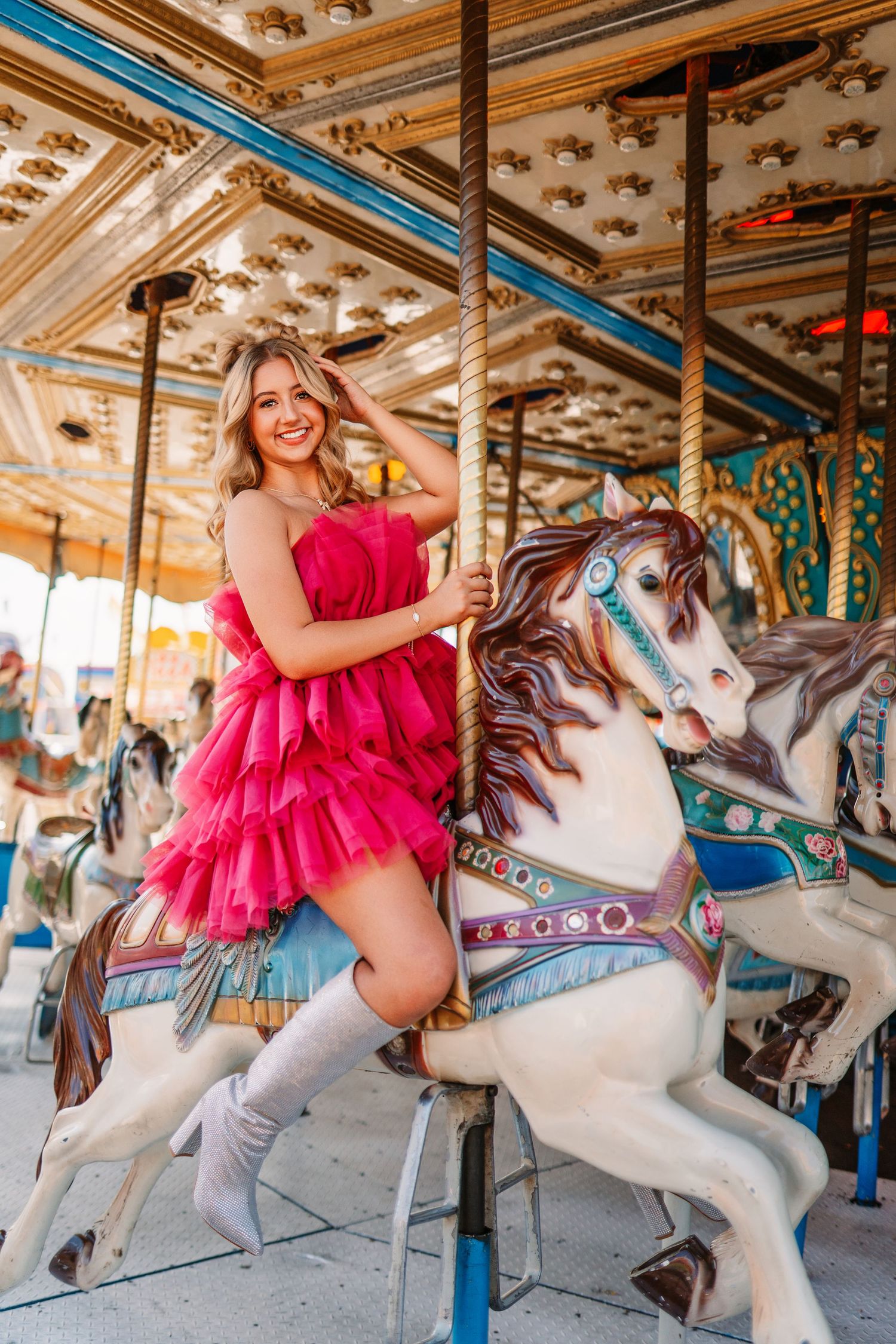 A playful carousel photoshoot with a white carousel horse and pink ruffled dress.