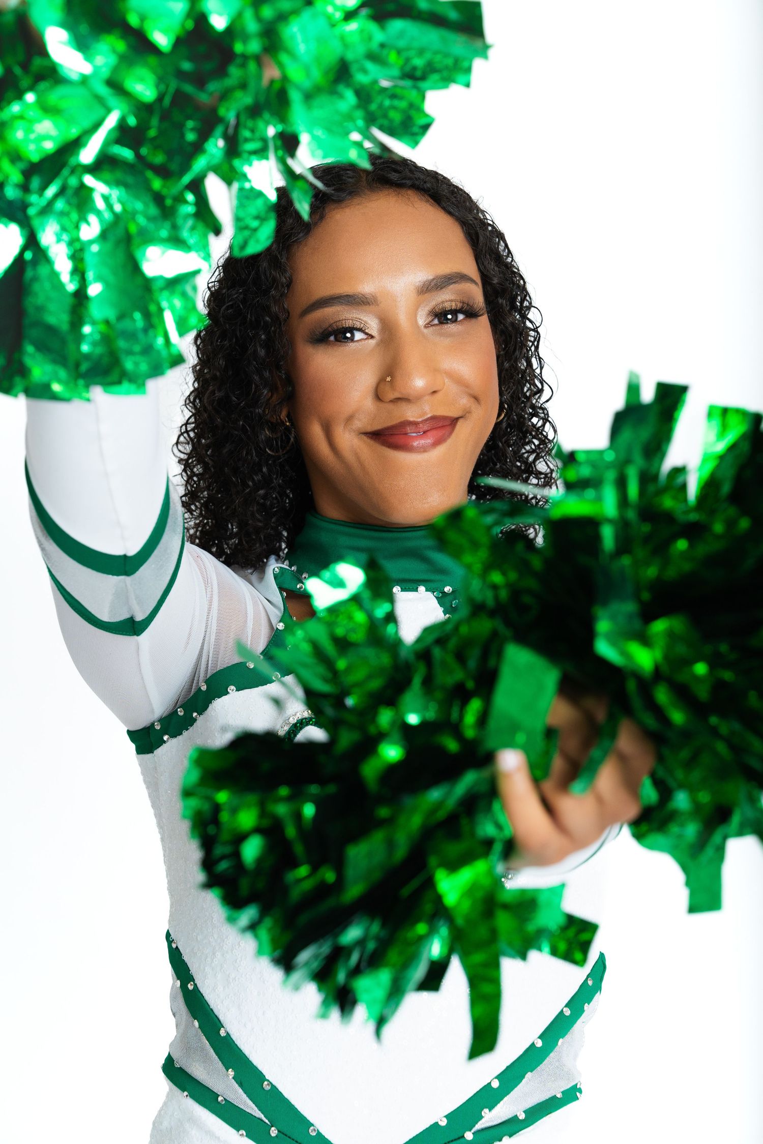 Cheerful portrait with bright green pom poms and a white uniform creating an energetic sports theme.