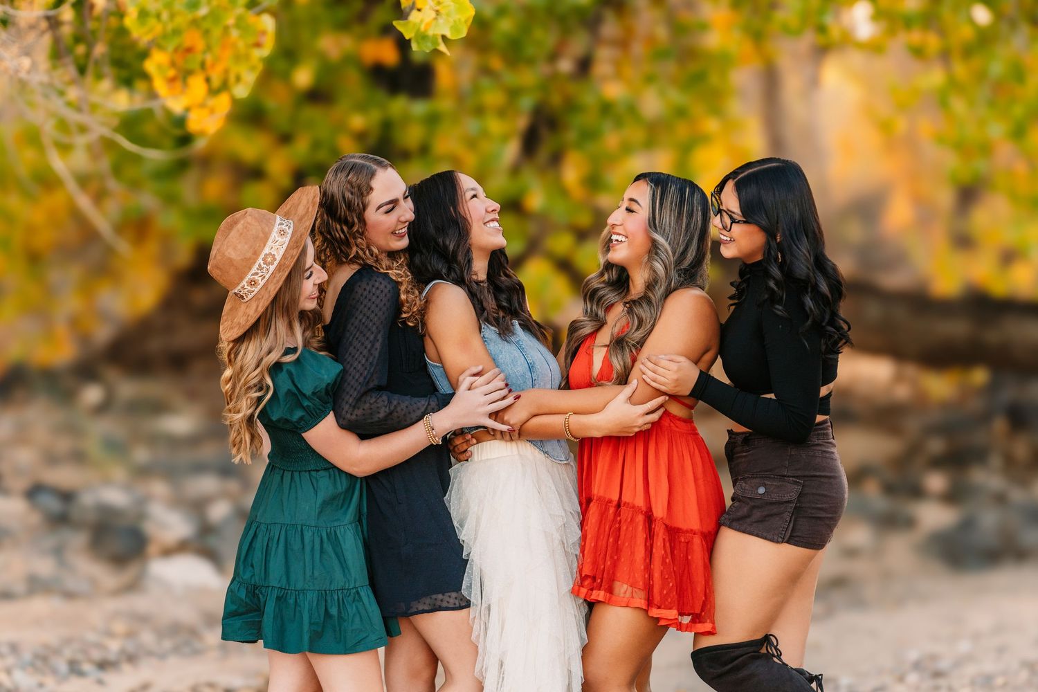 Group of friends laughing and hugging outdoors during golden hour.