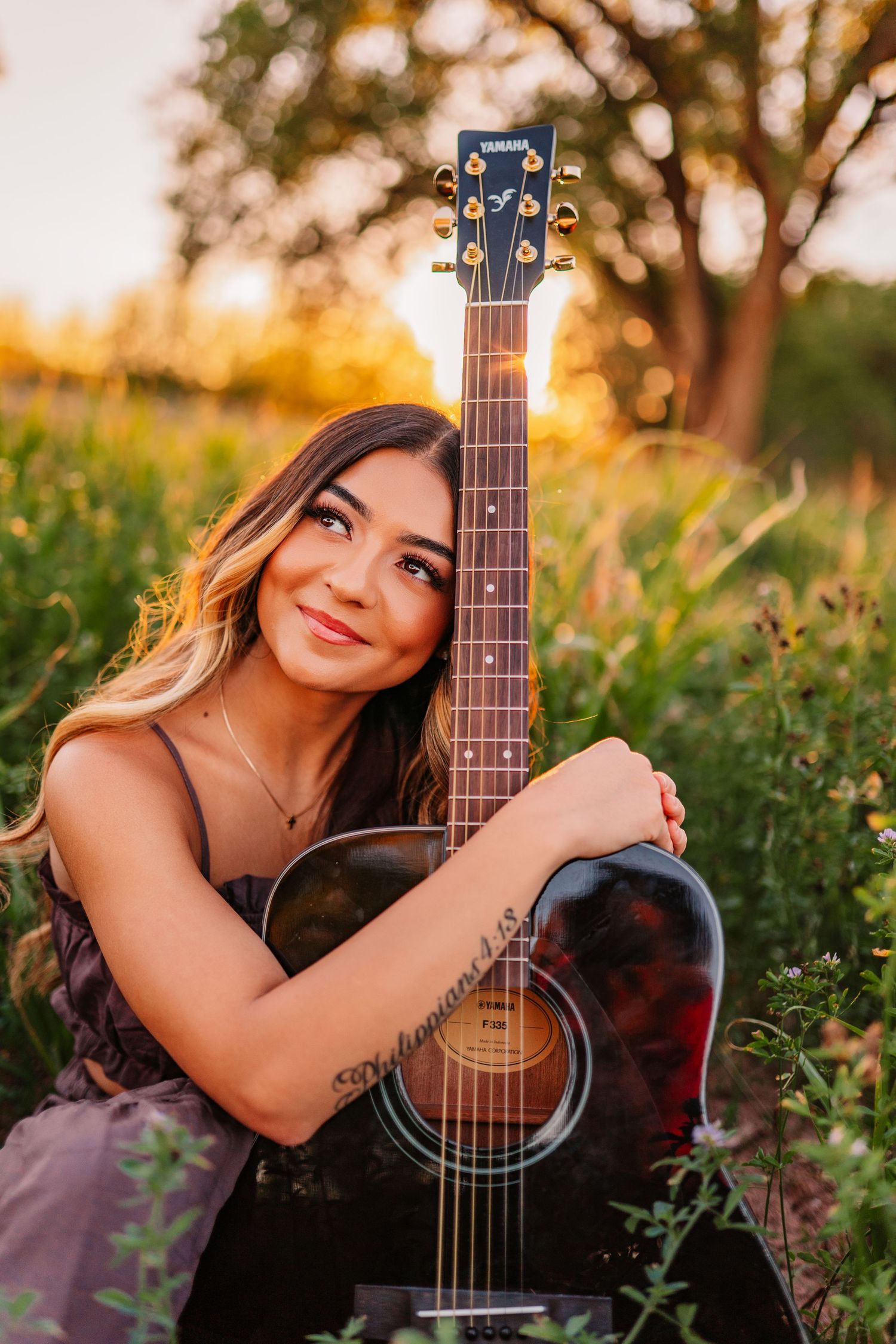 Acoustic guitar photoshoot in a field during golden hour sunset.