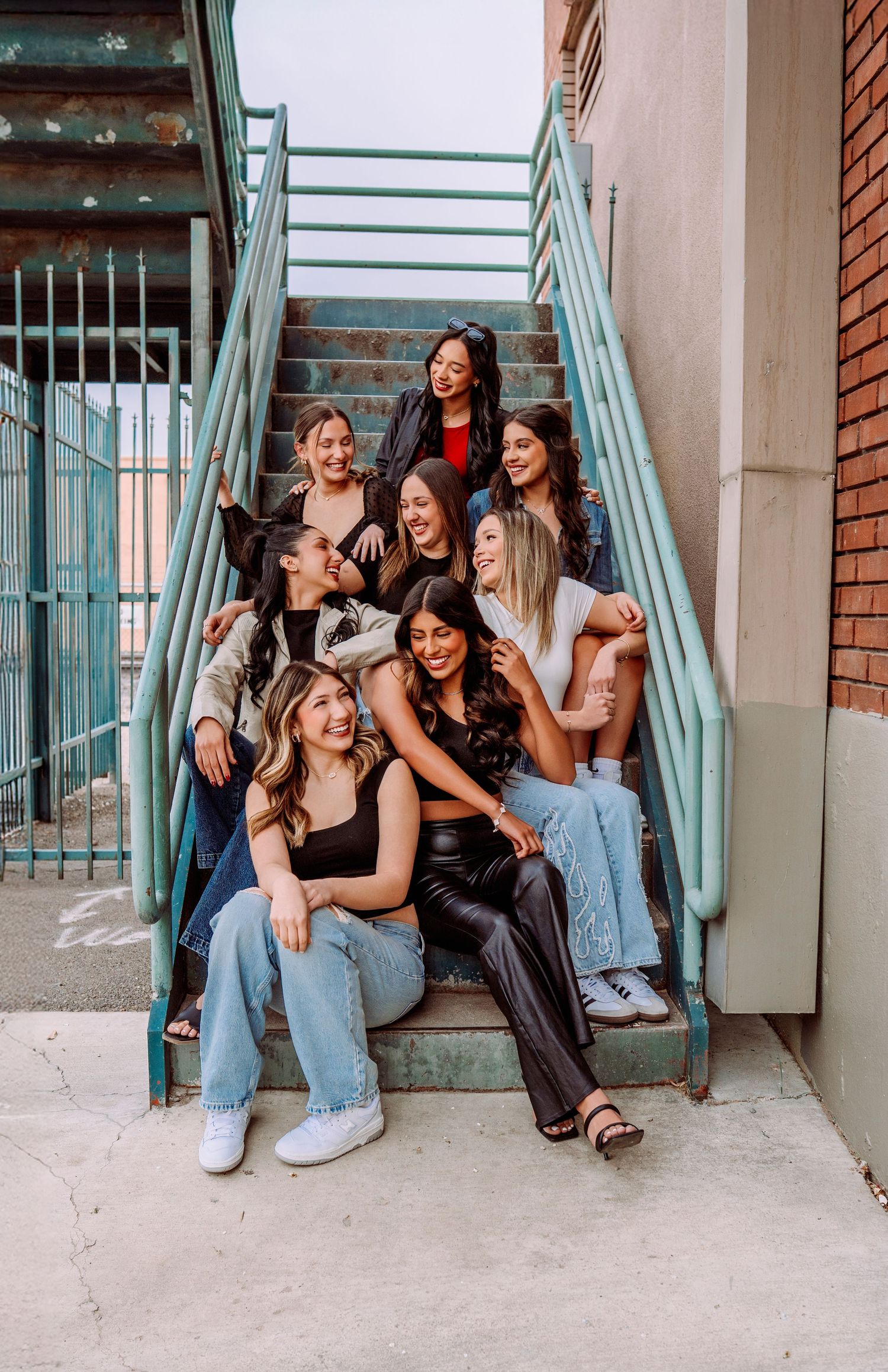 Candid group moment on industrial staircase wearing casual denim and black outfits.