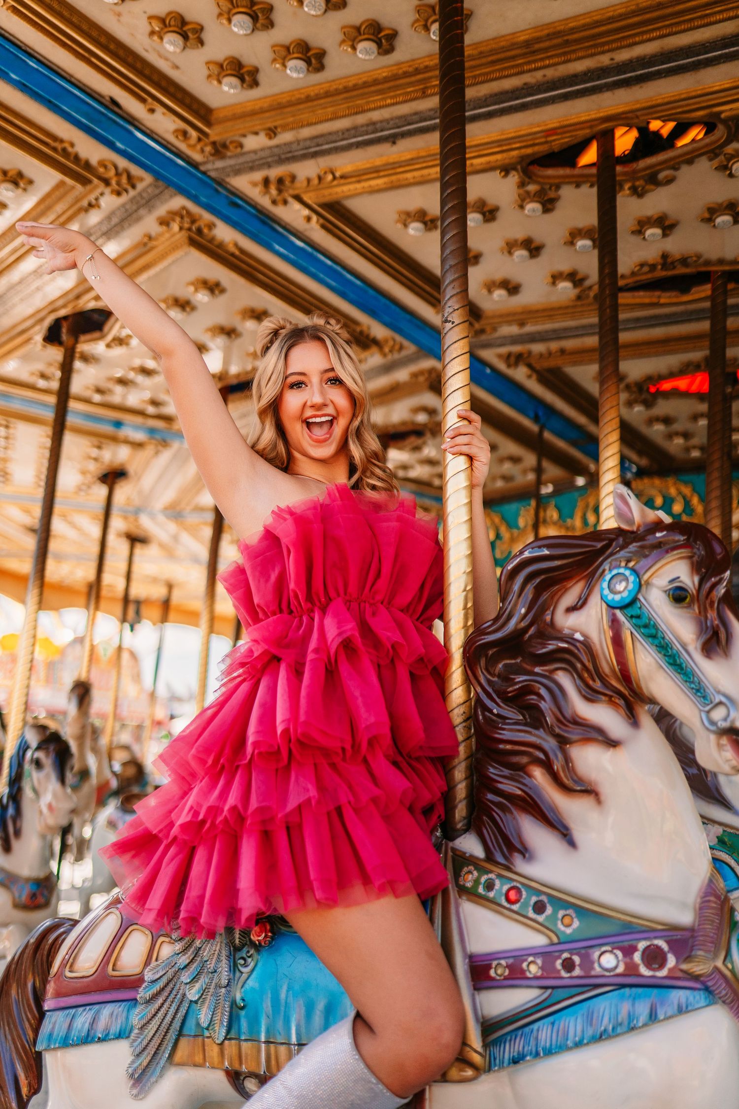 Vintage carousel horses decorated with ornate details beside pink tulle dress.