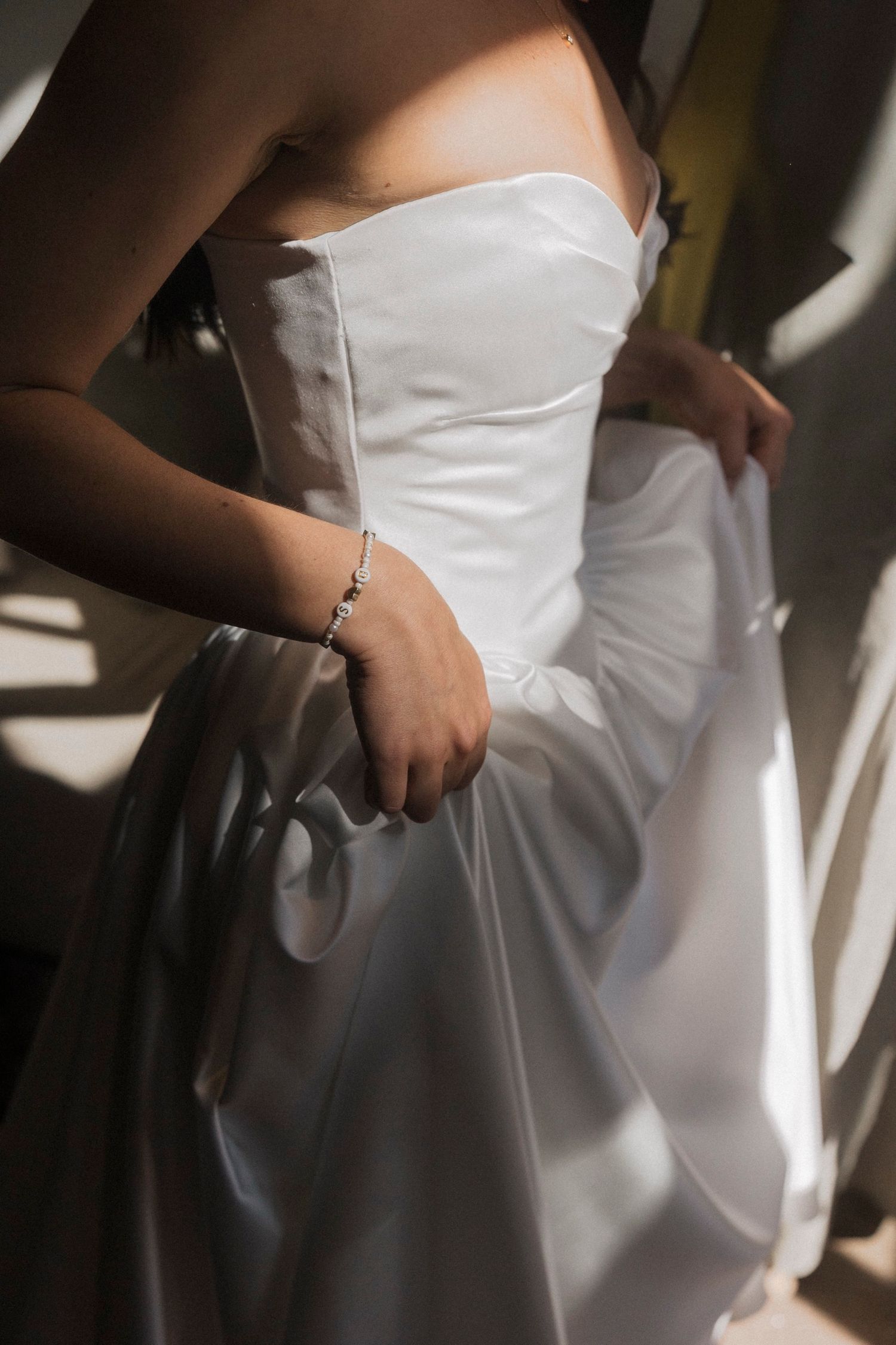 Close-up details of a white strapless wedding dress showing the structured bodice and waistline in natural light.