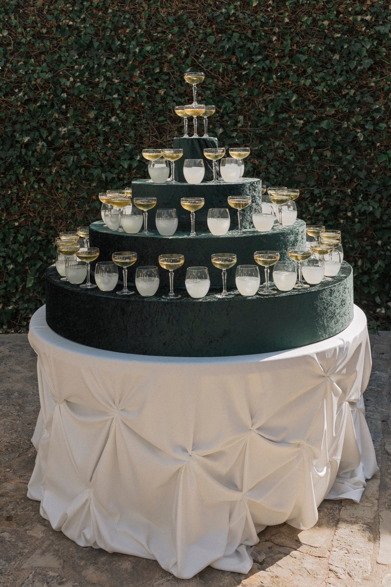 Tiered display of champagne glasses on round table with white pintuck tablecloth.