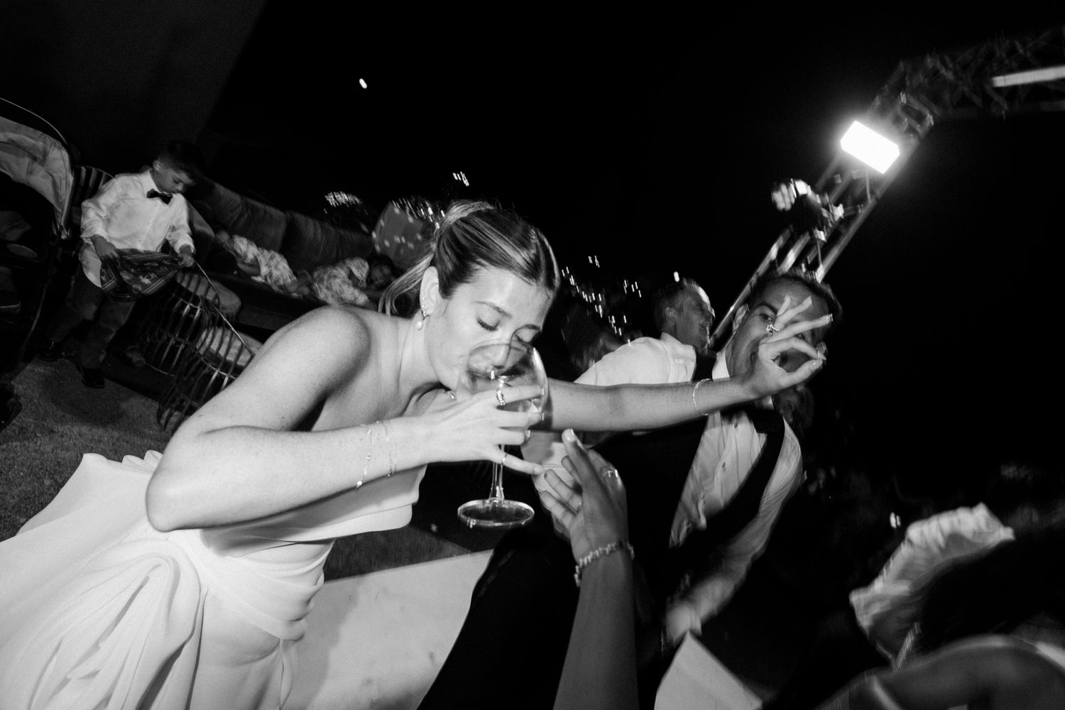 Black and white photo captures energetic dancing moment at wedding reception.
