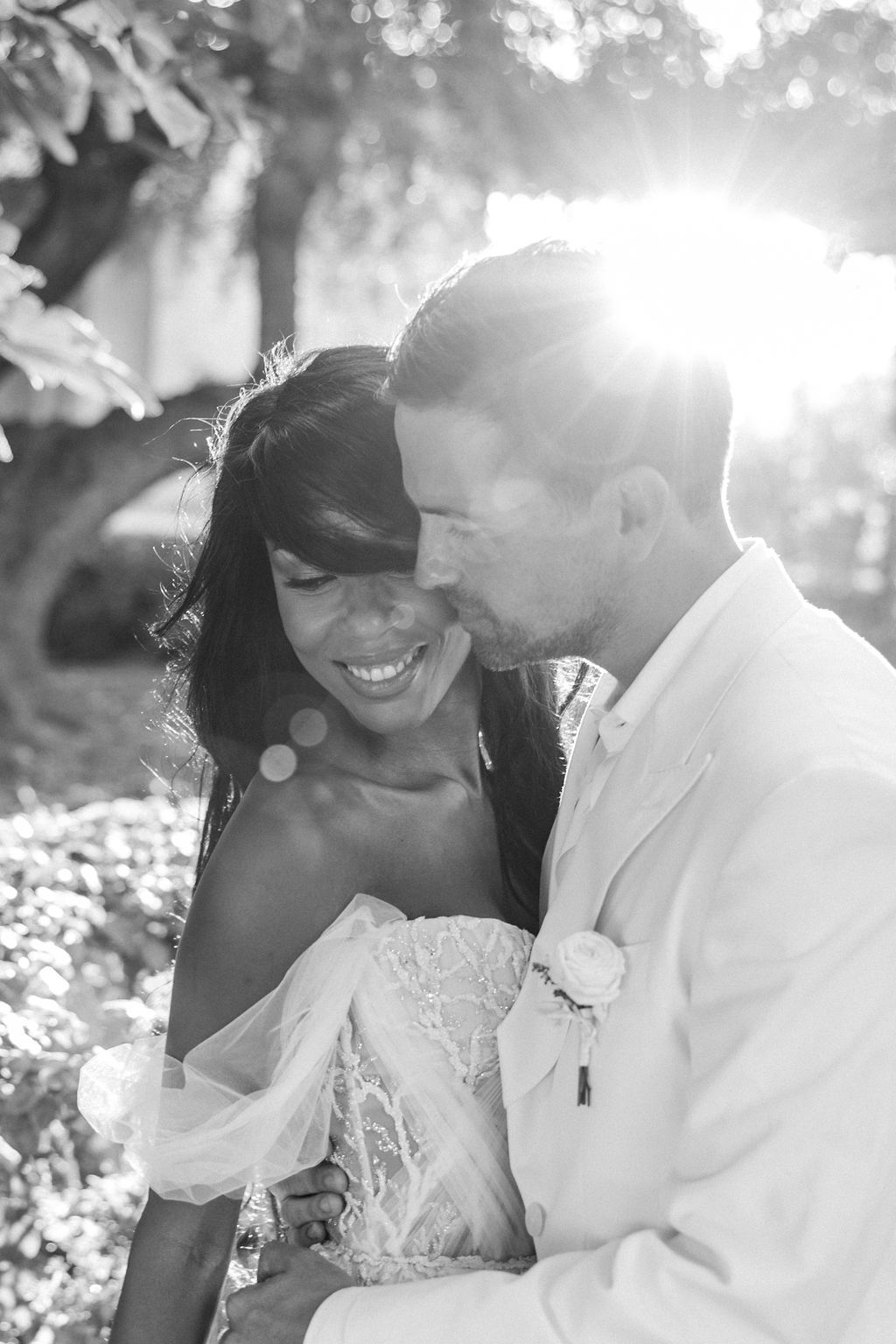 Intimate wedding couple shares romantic moments in a sun-drenched outdoor setting.