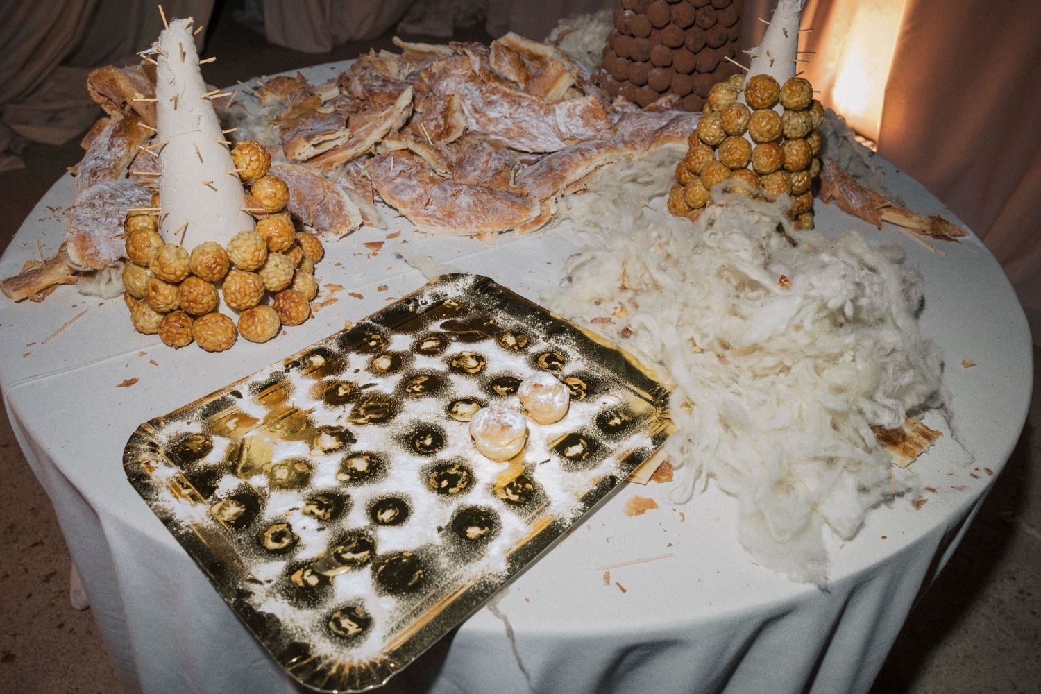 A dessert table displays various treats including macarons and pastries on a white tablecloth.