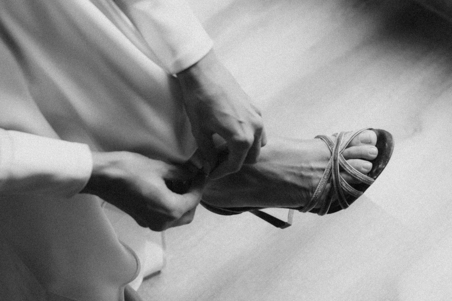 A dramatic black and white detail shot focusing on the hem of a flowing white dress.