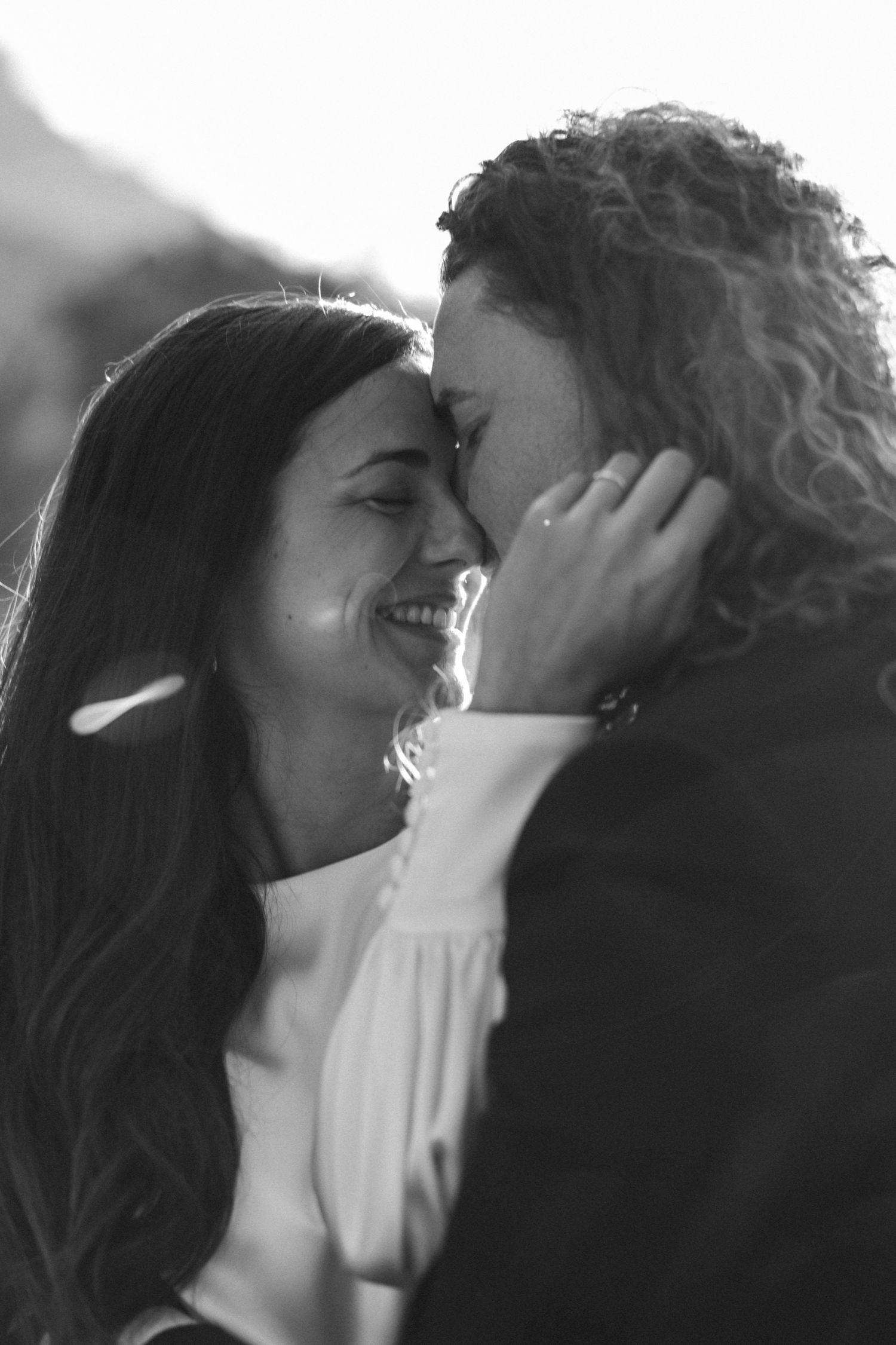 Black and white intimate portrait of a couple sharing a tender moment outdoors.