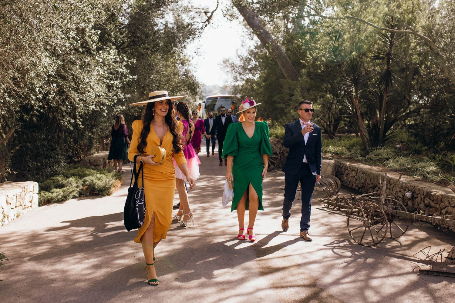 A group of well-dressed guests walking along a garden path at an outdoor event.