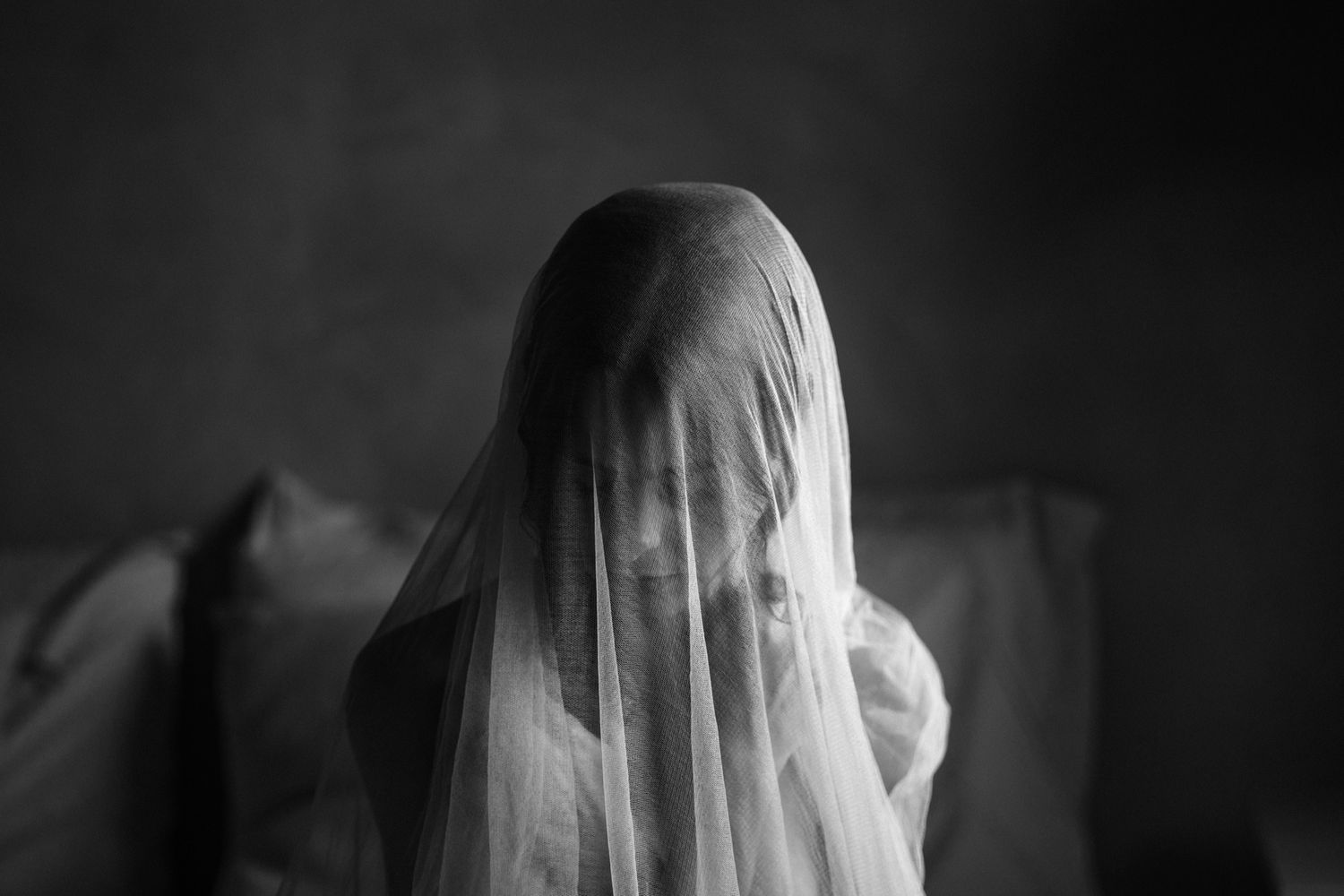A haunting black and white photo series shows a ghostly figure in a white veil against dark backgrounds.