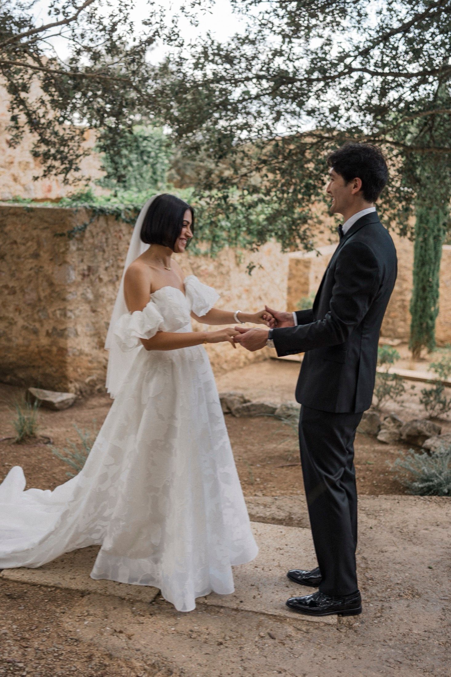 A romantic first dance sequence captured outdoors in a rustic garden setting with natural lighting and stone walls.