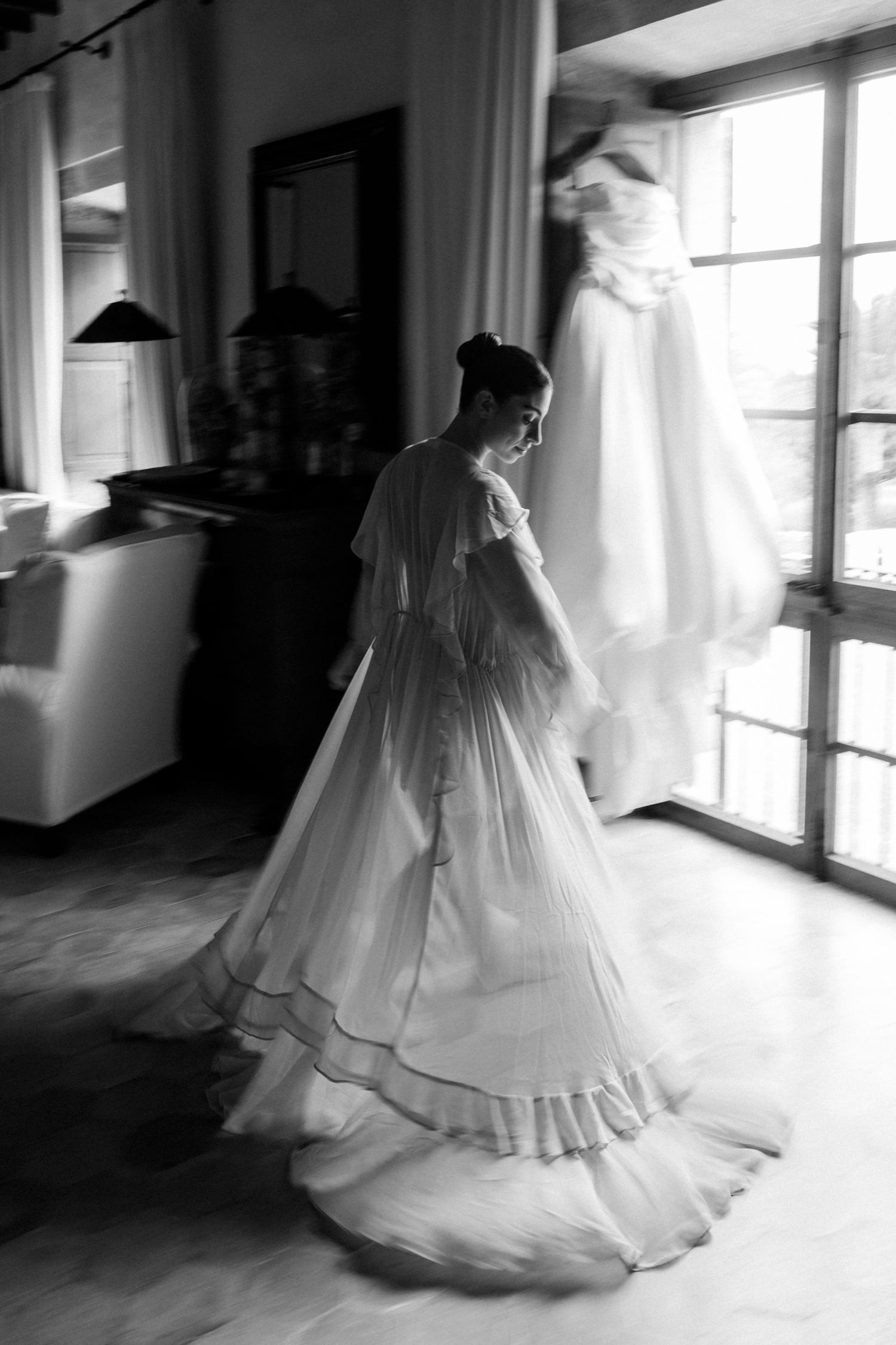 A series of black and white photos showing a bride in a flowing wedding gown twirling near sunlit windows.