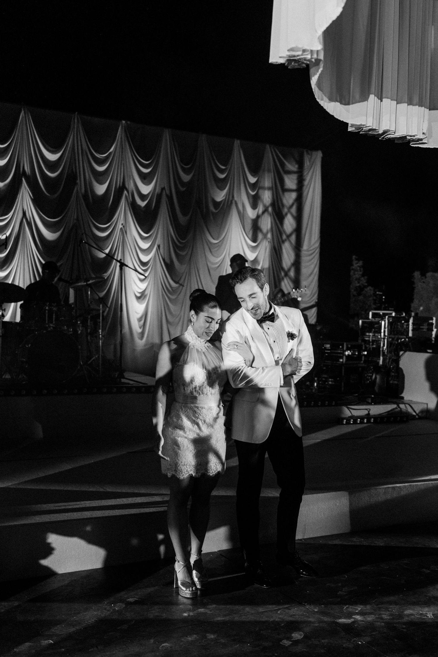 Two performers dance together on stage in front of elegant draped curtains in this vintage black and white photograph.